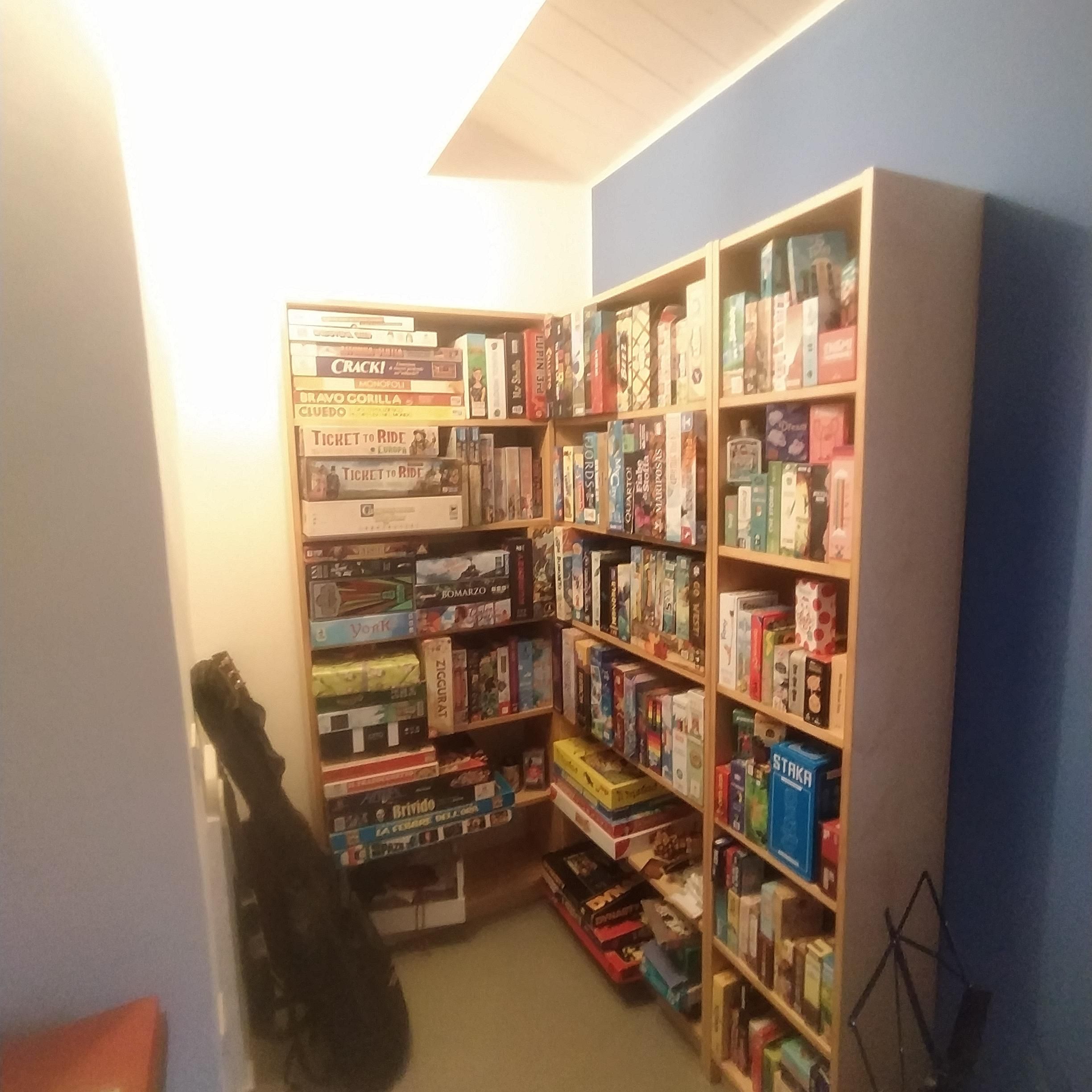 Nella foto ci sono delle librerie piene di giochi da tavolo illuminati con una luce diretta 