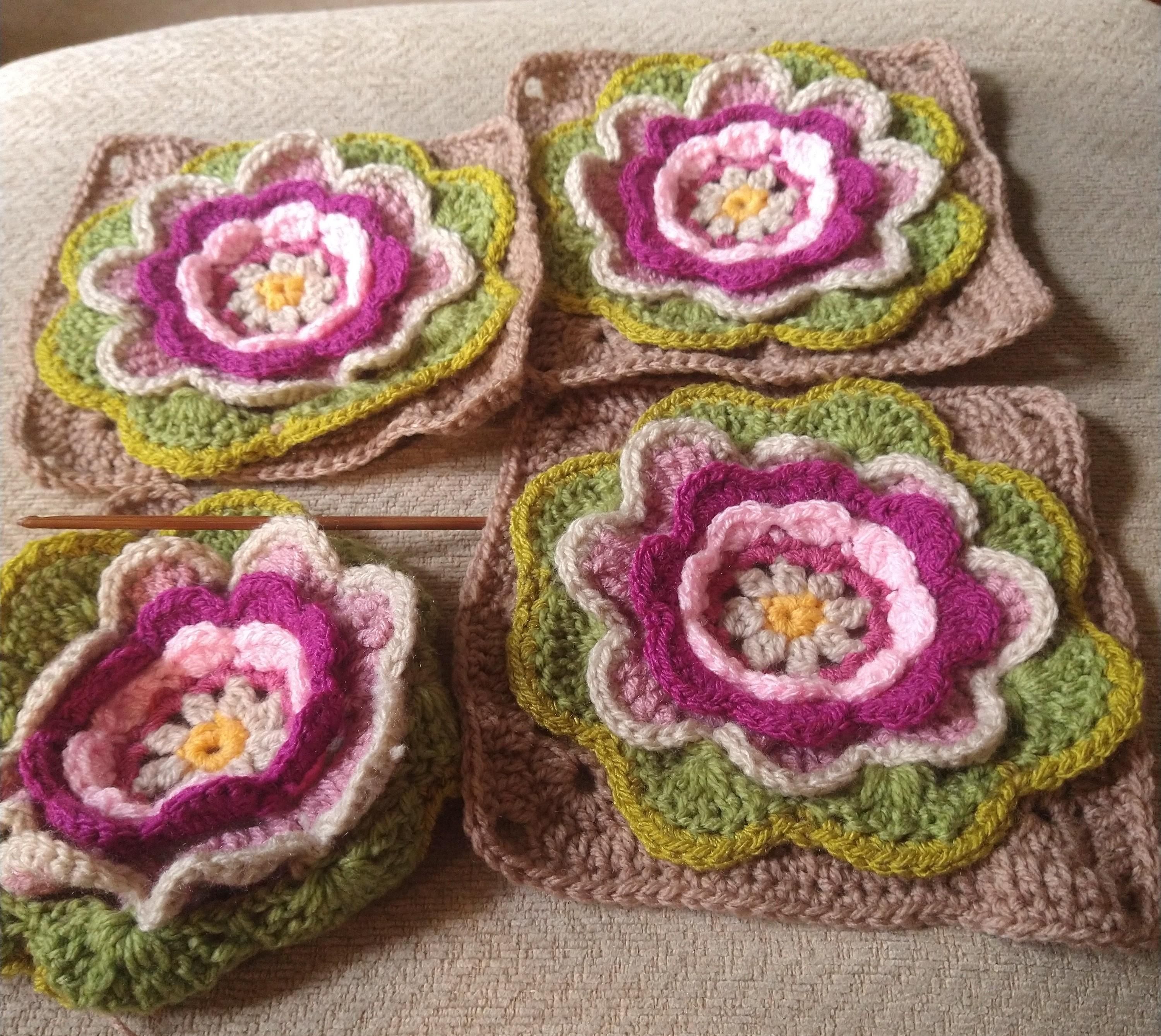 Four crochet motifs, three are completed squares with flower centres one on the bottom left is waiting for two final rounds 