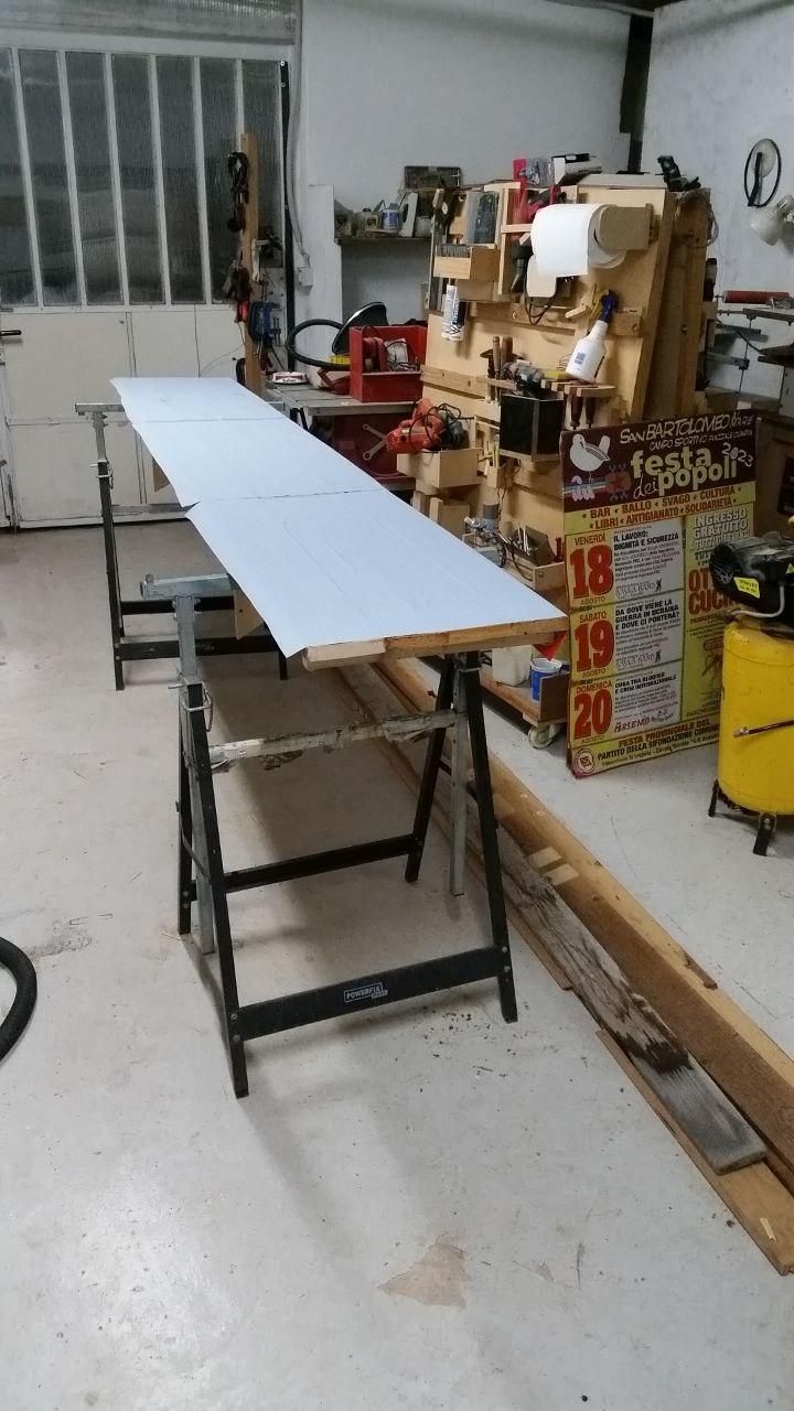 Quattro tavole avvitate insieme, rivestite con manifesti vecchi rivoltati, appoggiate su due cavalletti.