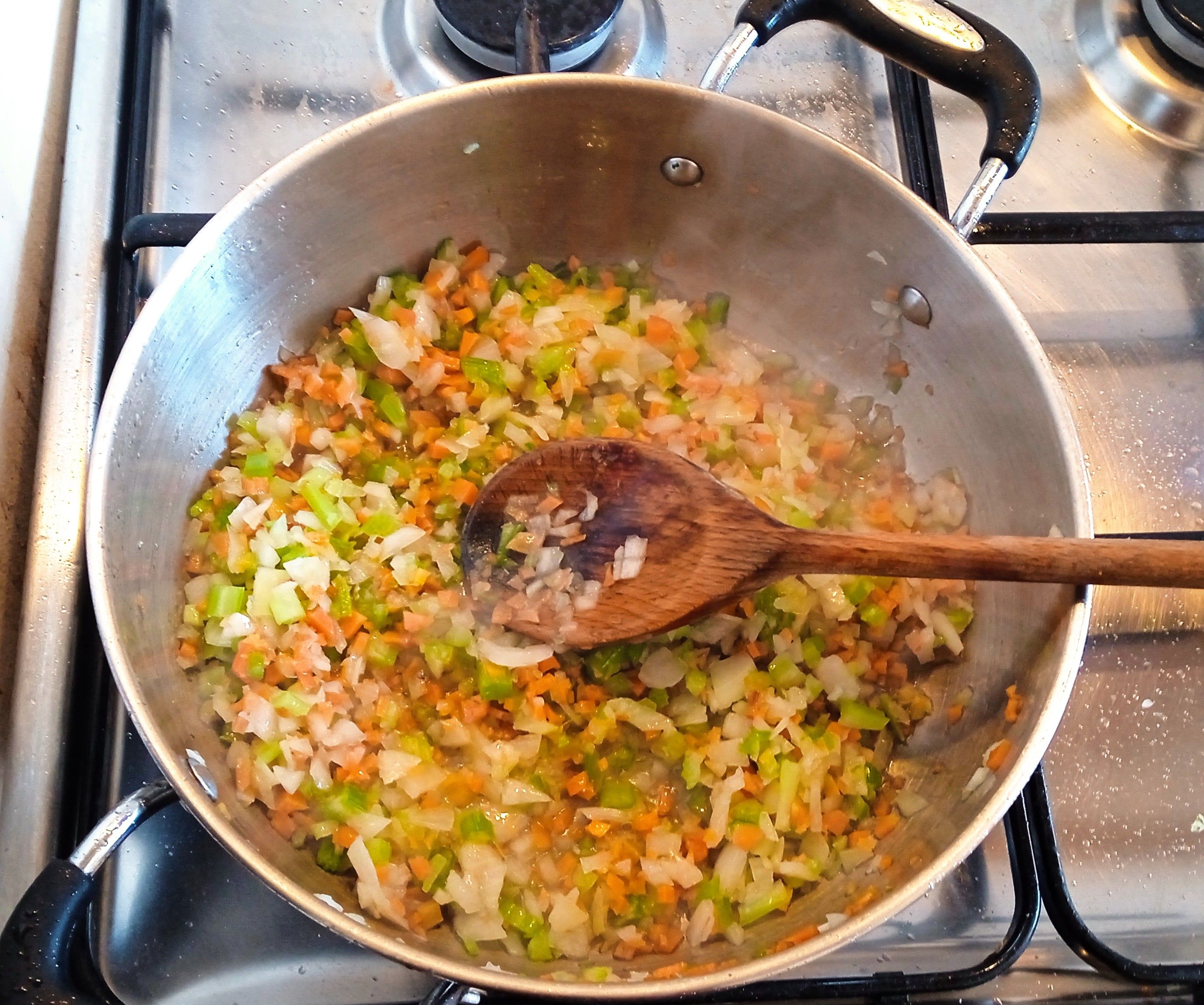 A sauté celery, carrot, and onion in a pan on the stove