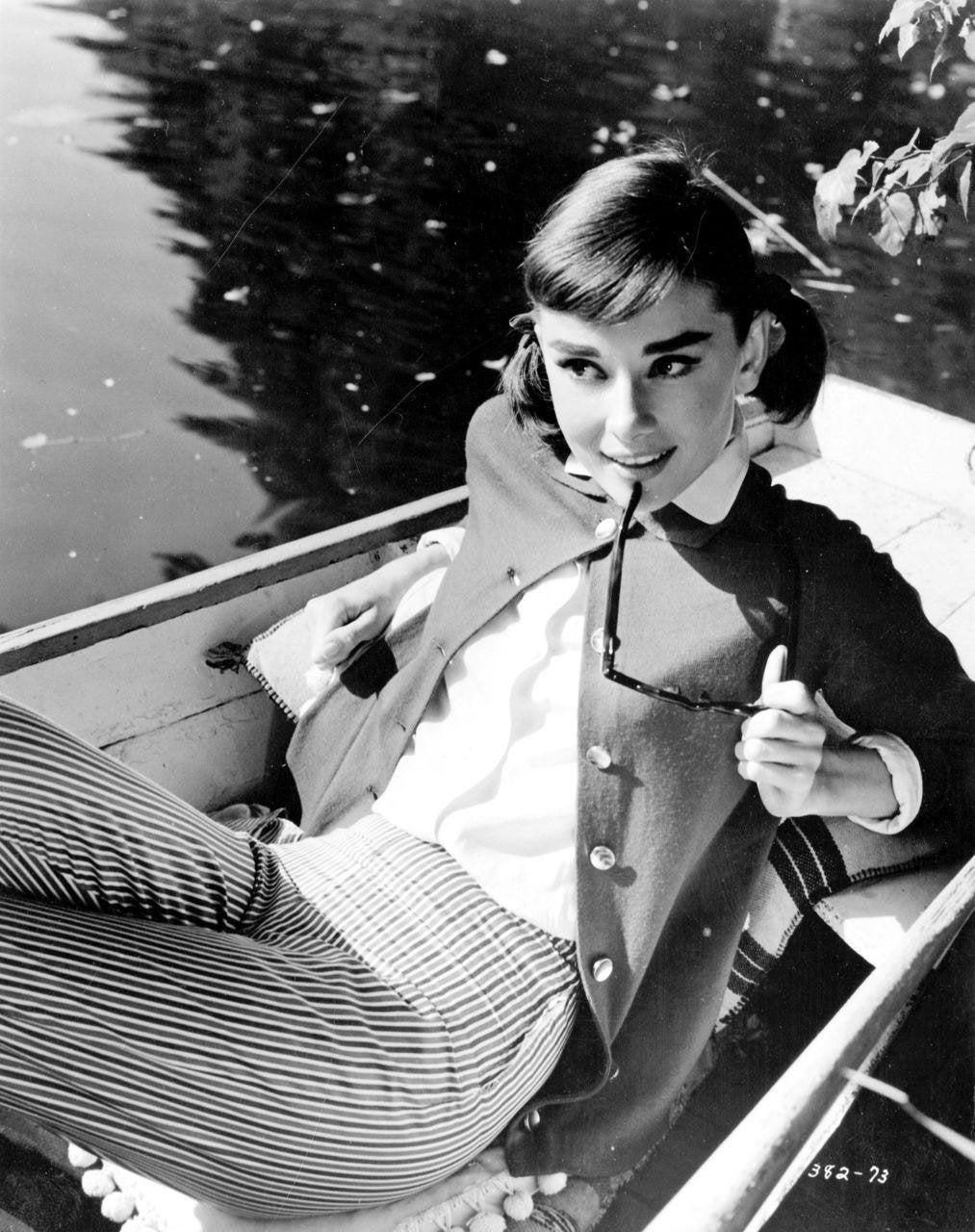 Audrey chews on her sunglasses as she reclines in a boat. 