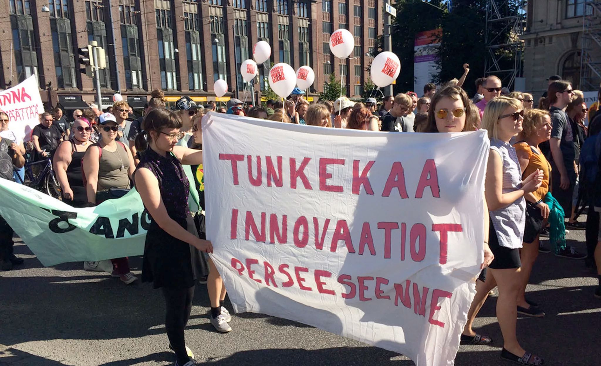 Lehtikuva mielenosoituksesta, jossa lakana tekstillä "Tunkekaa innovaatiot perseeseenne"