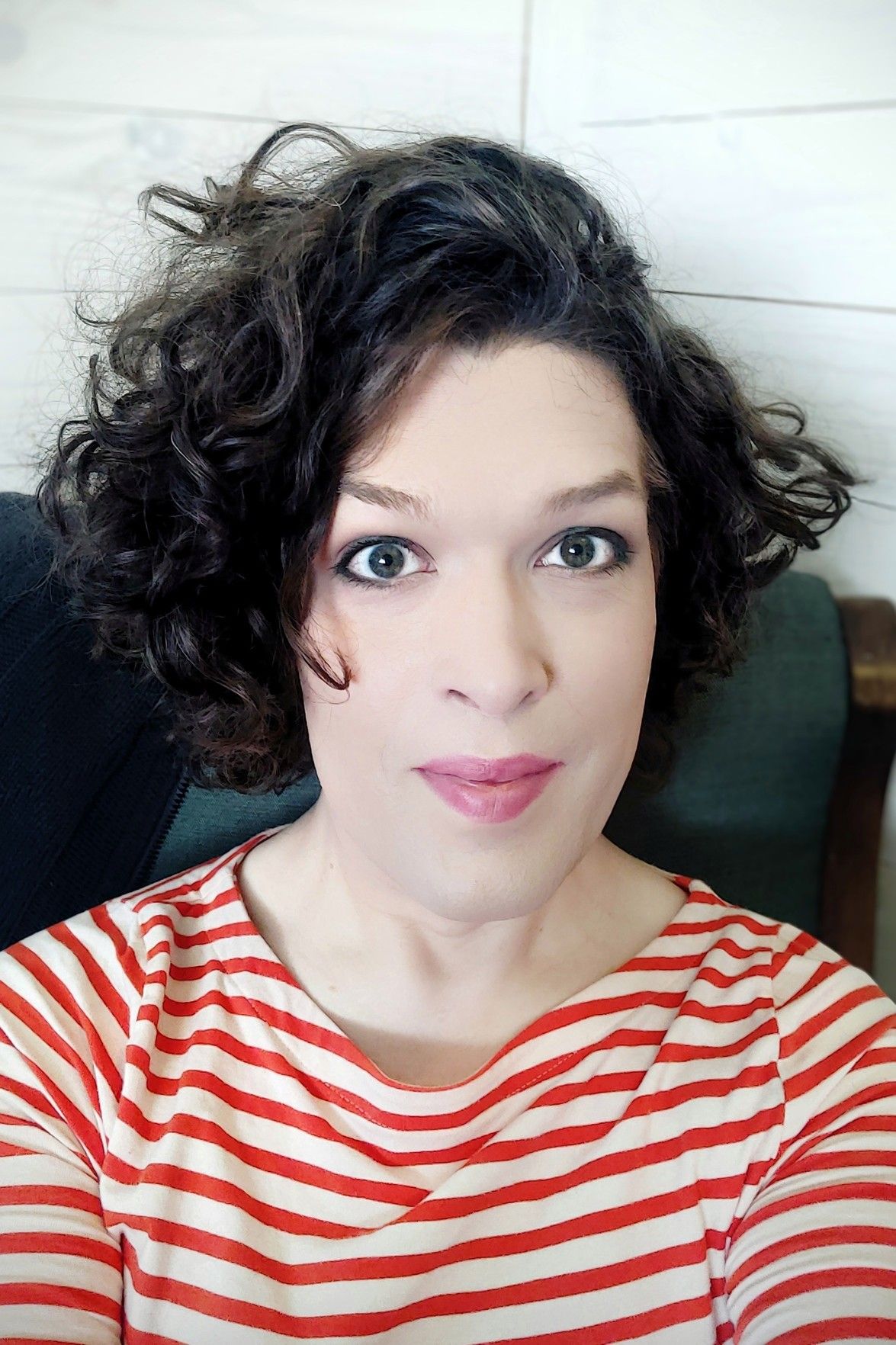 selfie in my armchair, smiling happily, hair to the side, orange and white horisontally striped top