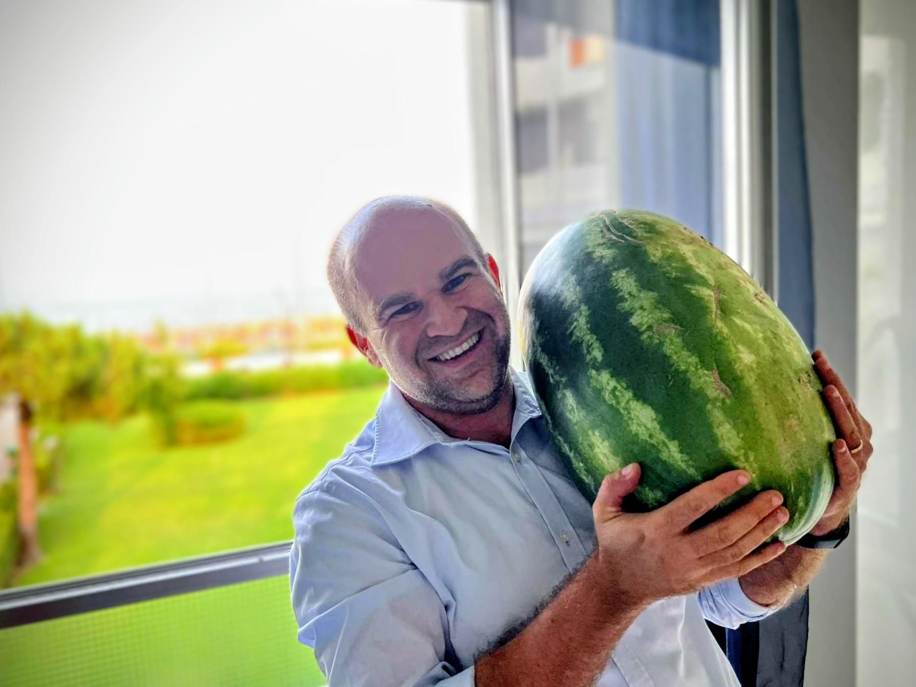 Me, holding a 16 kgs watermelon in front of a window.