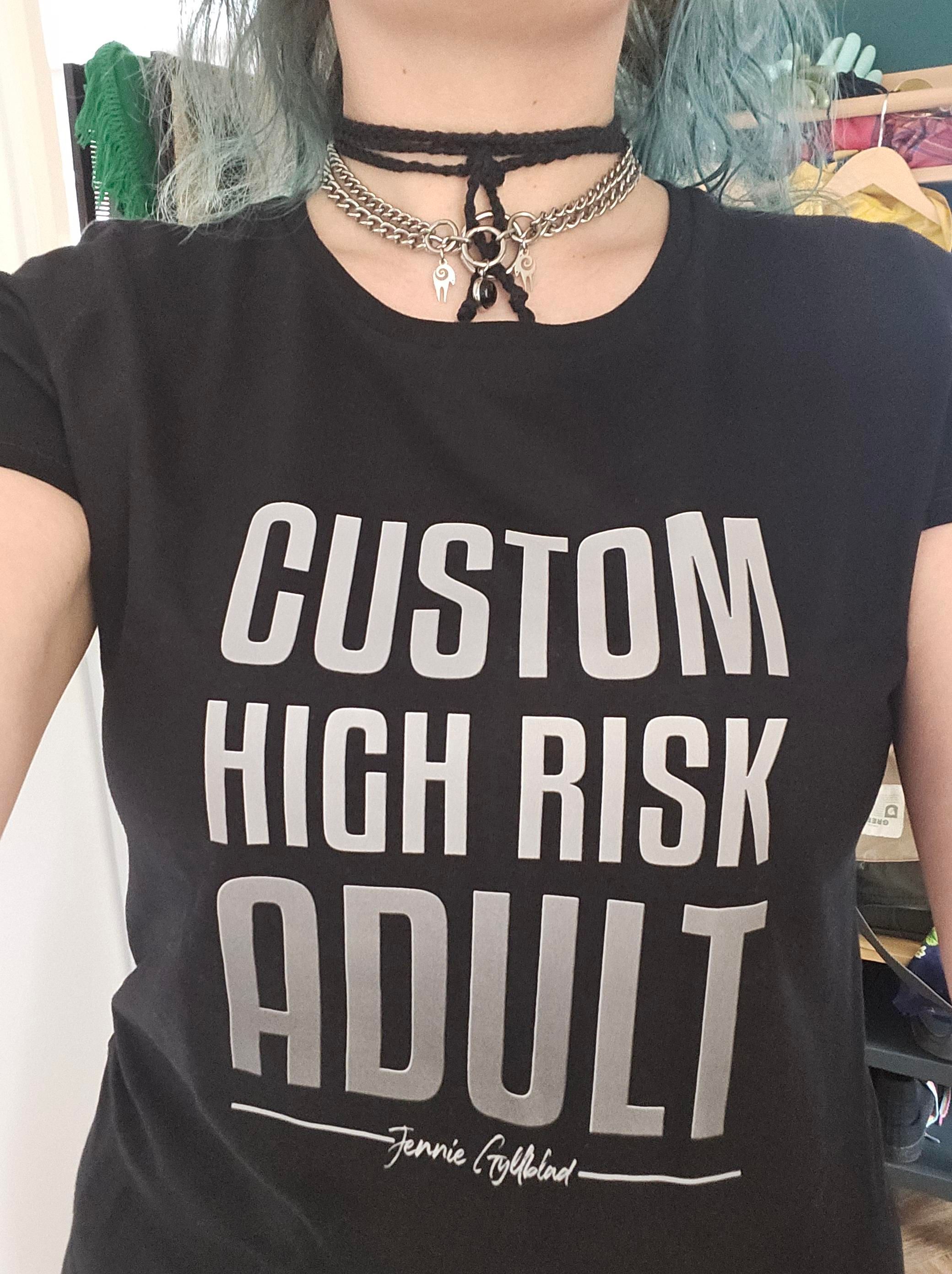 A tshirt that says CUSTOM HIGH RISK ADULT with a small cursive writing on the bottom saying Jennie Gyllblad
