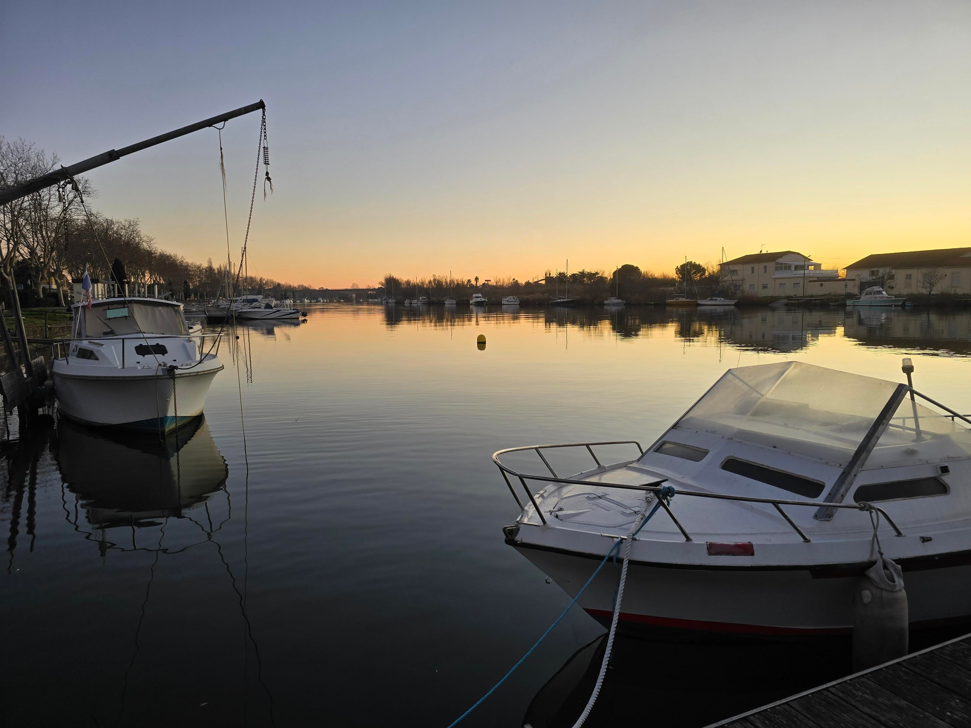 Deux bateaux de plaisance au bord de l'eau à Agde, au soleil couchant.