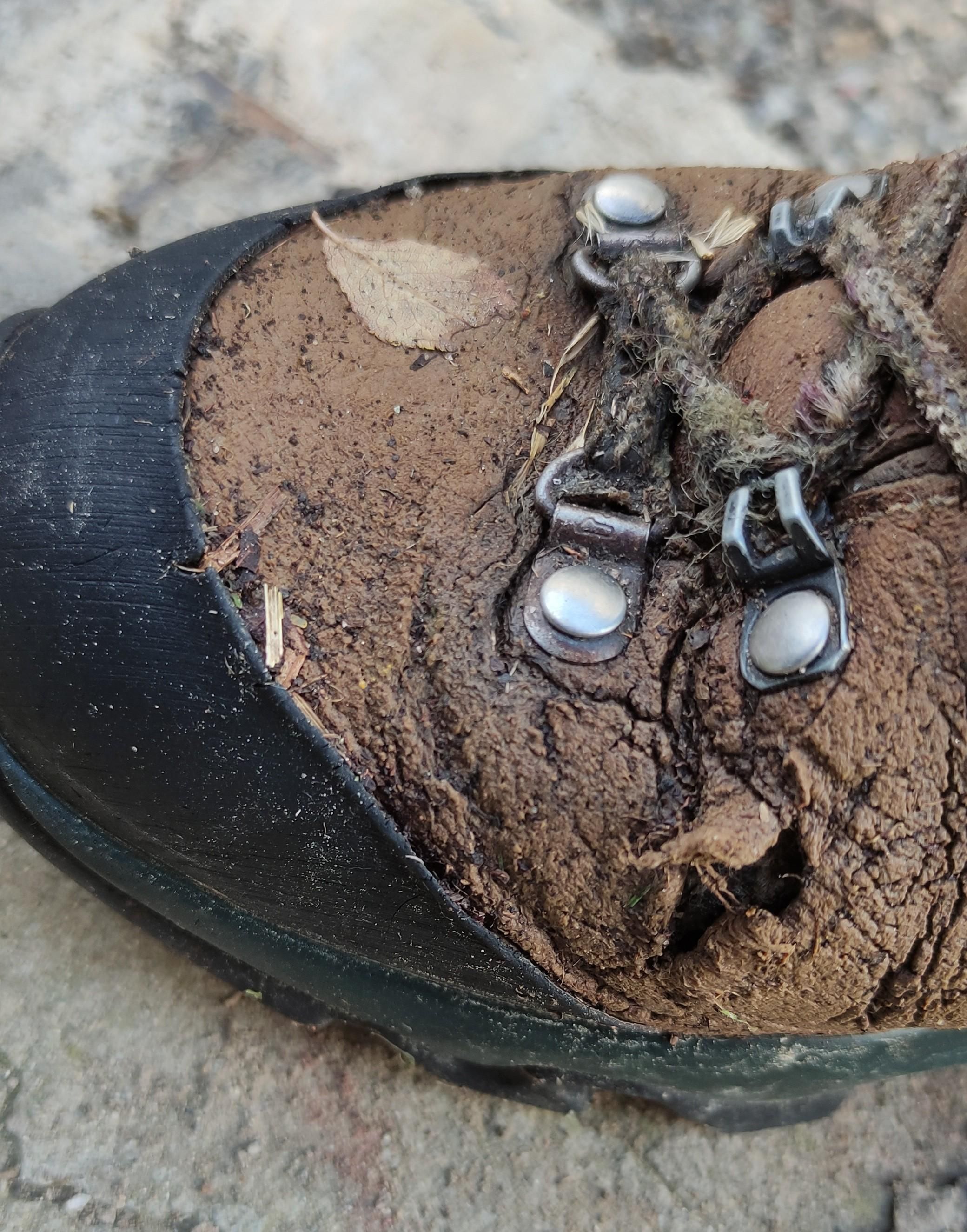 punta di scarpone destro completamente spappolato, cuoio bucato, lacci strappati, gomma in decomposizione 