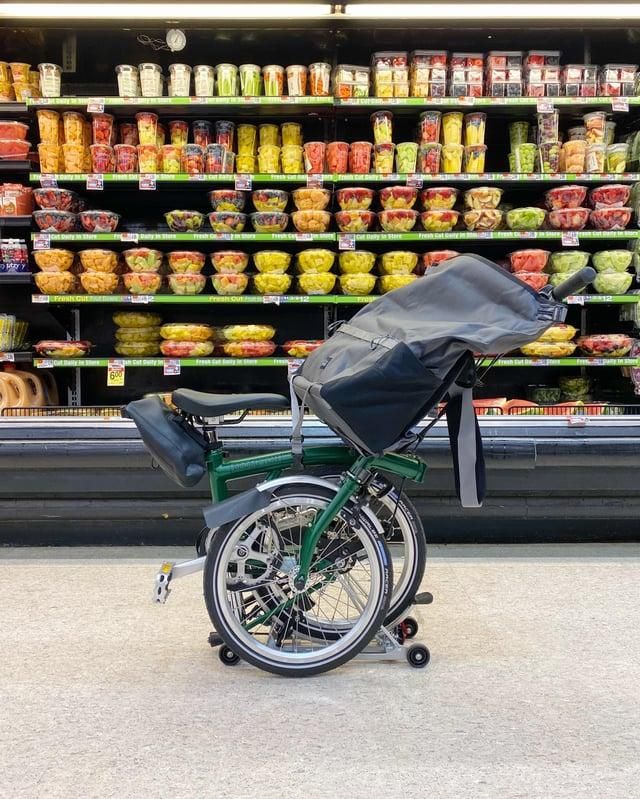 Bicicletta Brompton ripiegata, con la borsa aperta, all'interno di un supermercato.