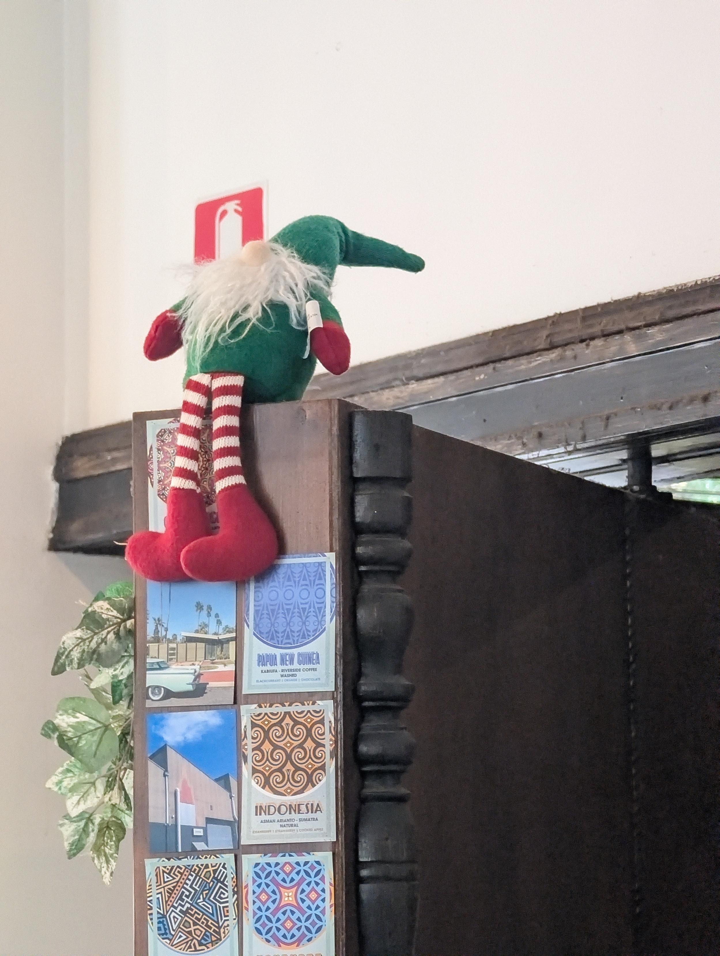 Elf on the shelf sitting on top of a bookcase