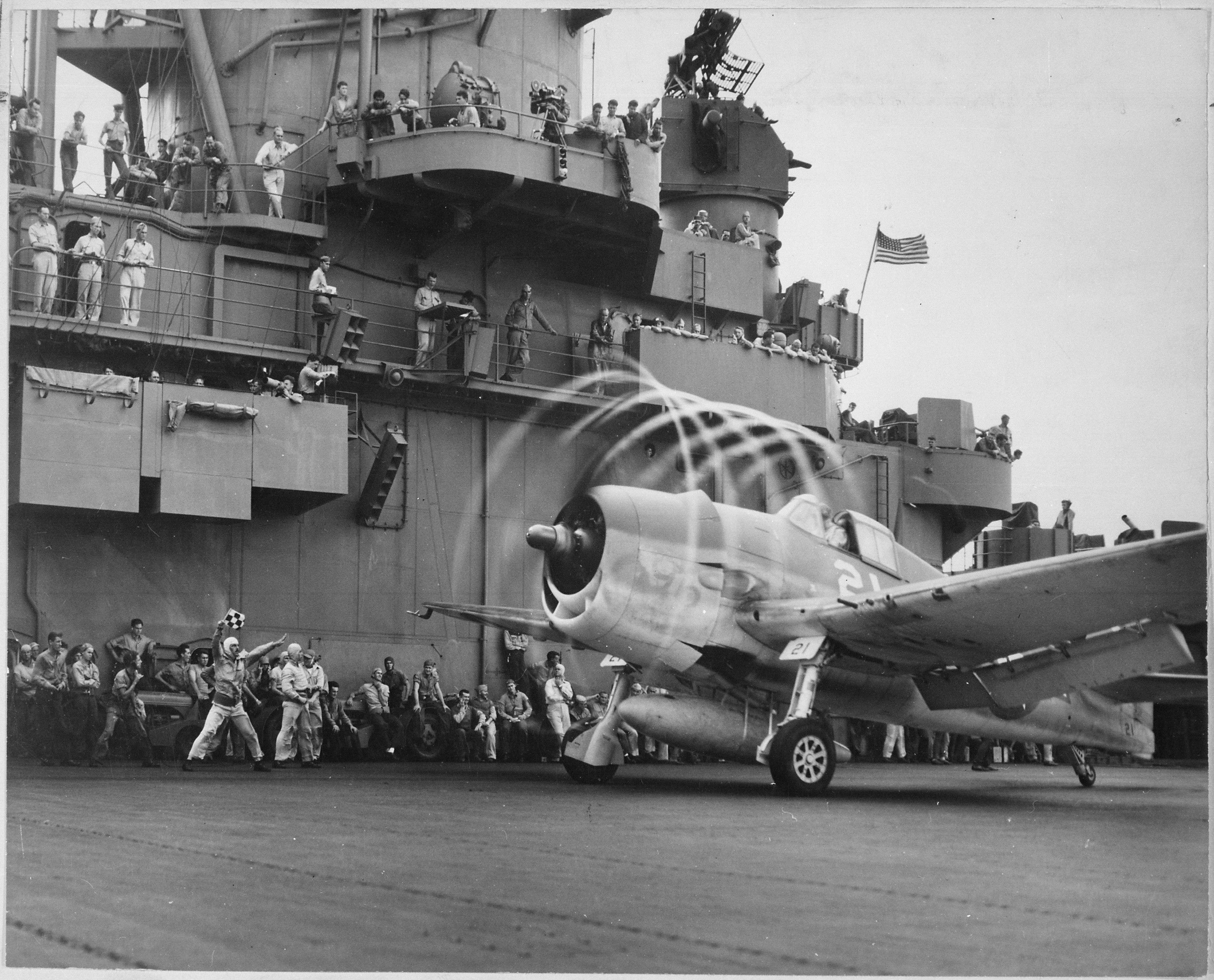 The motion of its props causes an "aura" to form around this F6F on USS YORKTOWN. Rapid change of pressure and drop in temperature create condensation. Rotating with blades, halo moves aft, giving depth and perspective.