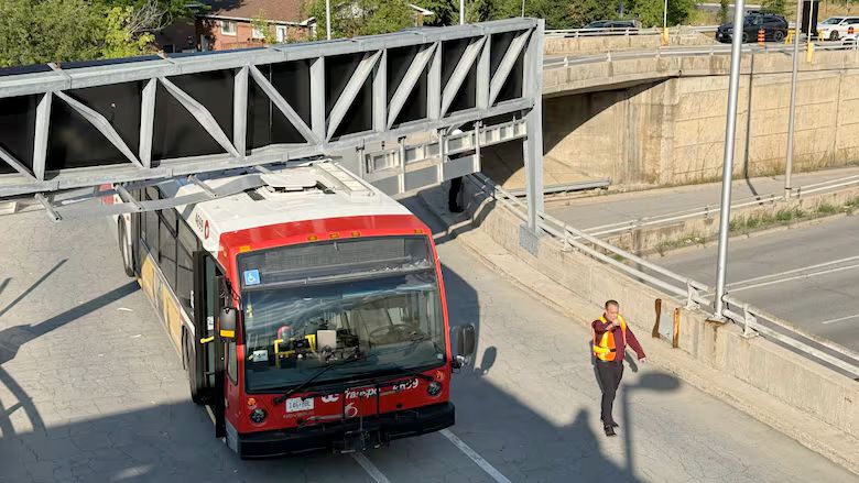 IC trabspo bus stuck under an overhead structure that holds a sign on a road 
