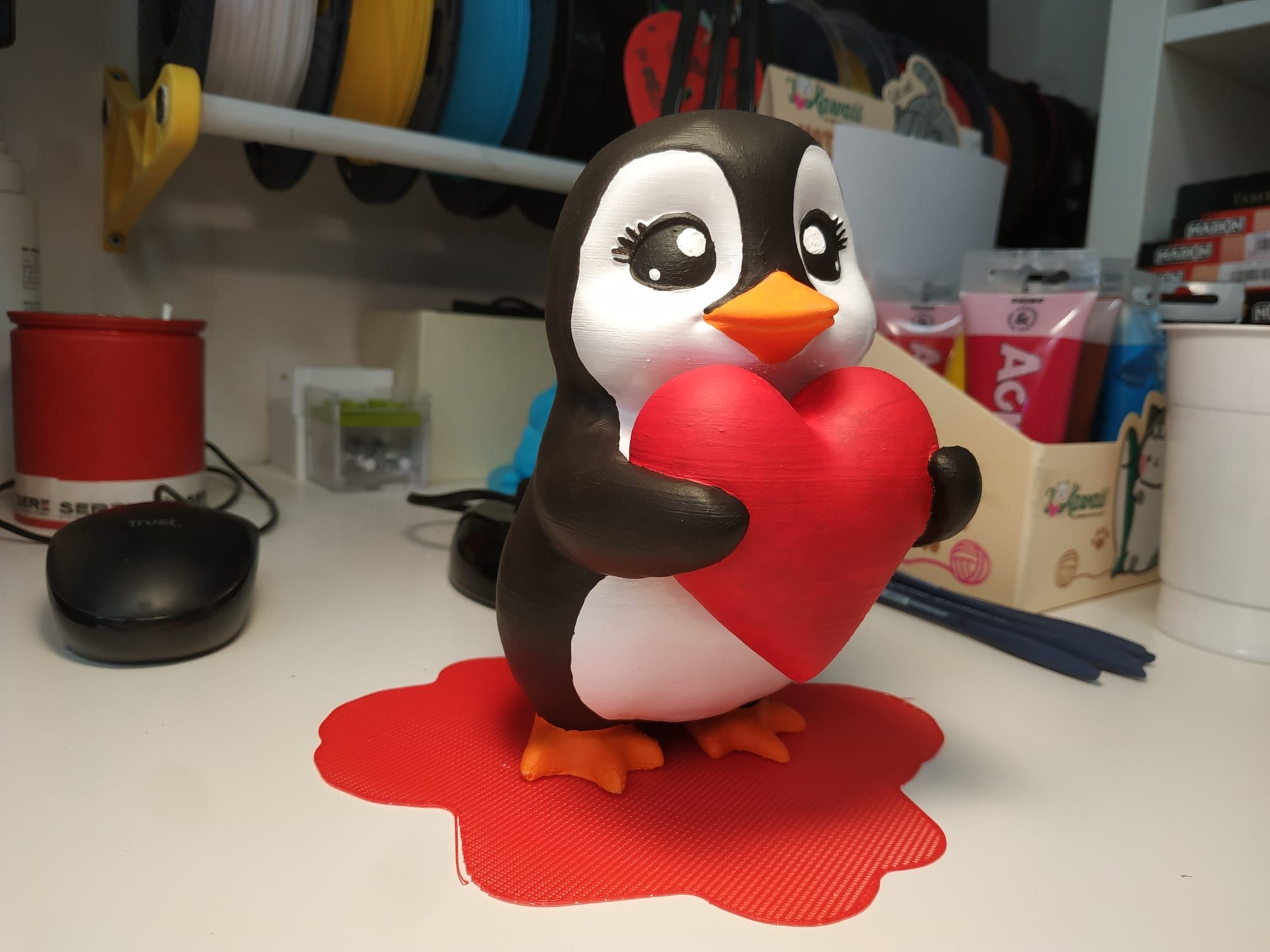 Pinguino dipinto a mano che regge un grosso cuore rosso.
Paccottiglia nello sfondo.