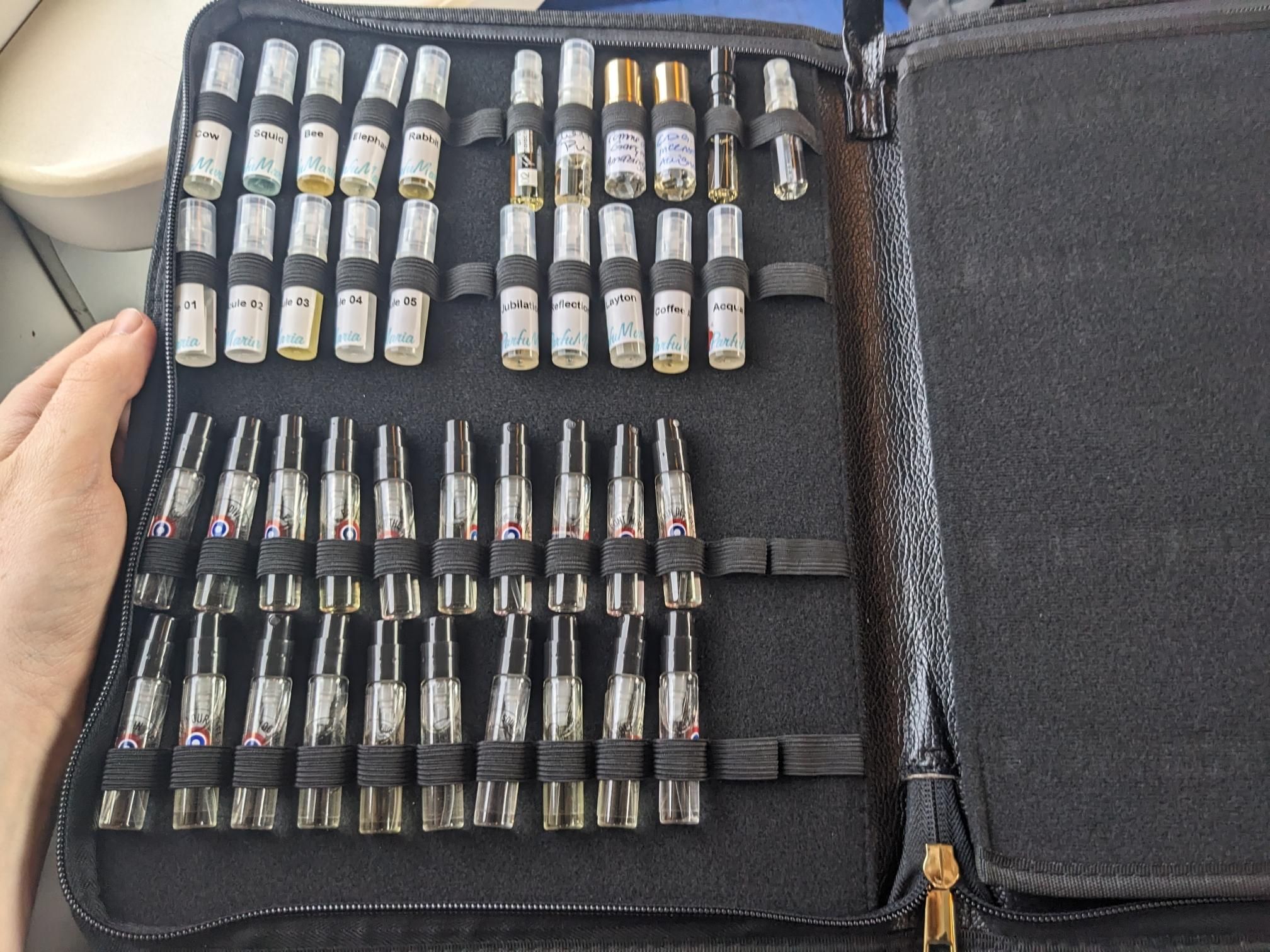 Around fourty little perfume spray bottles in a black case.