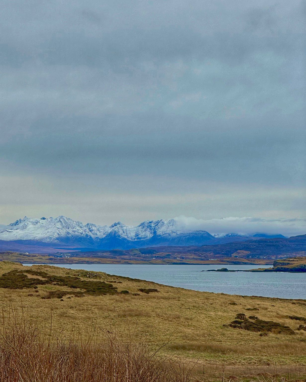 The snow capped Cuillin range seen from Harlosh on Loch Bracadale near Dunvegan on the Isle of Skye. They are putting love on me. Purple-blue and white beyond a winter shore. And breathe…  