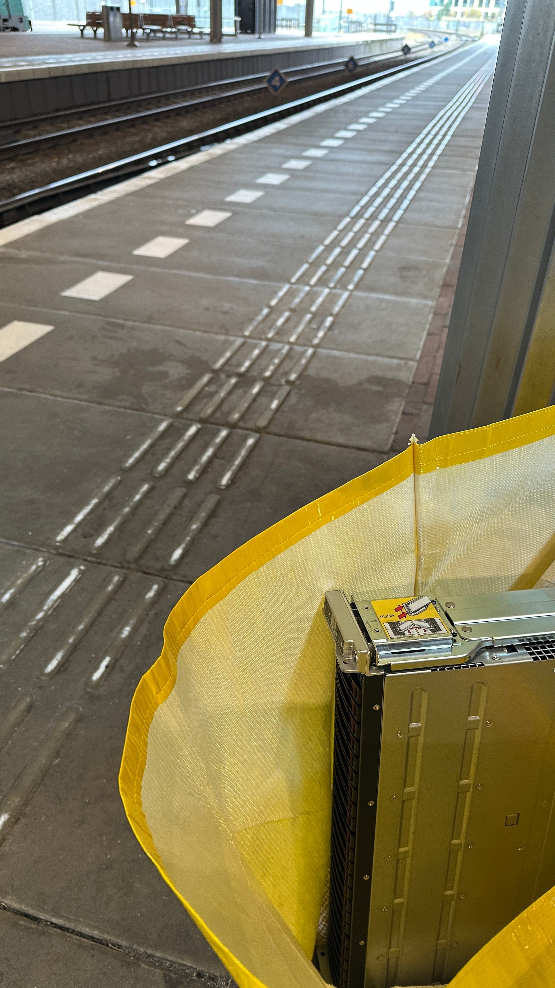 Yellow bag with a 2u server in it next to a train platform. 