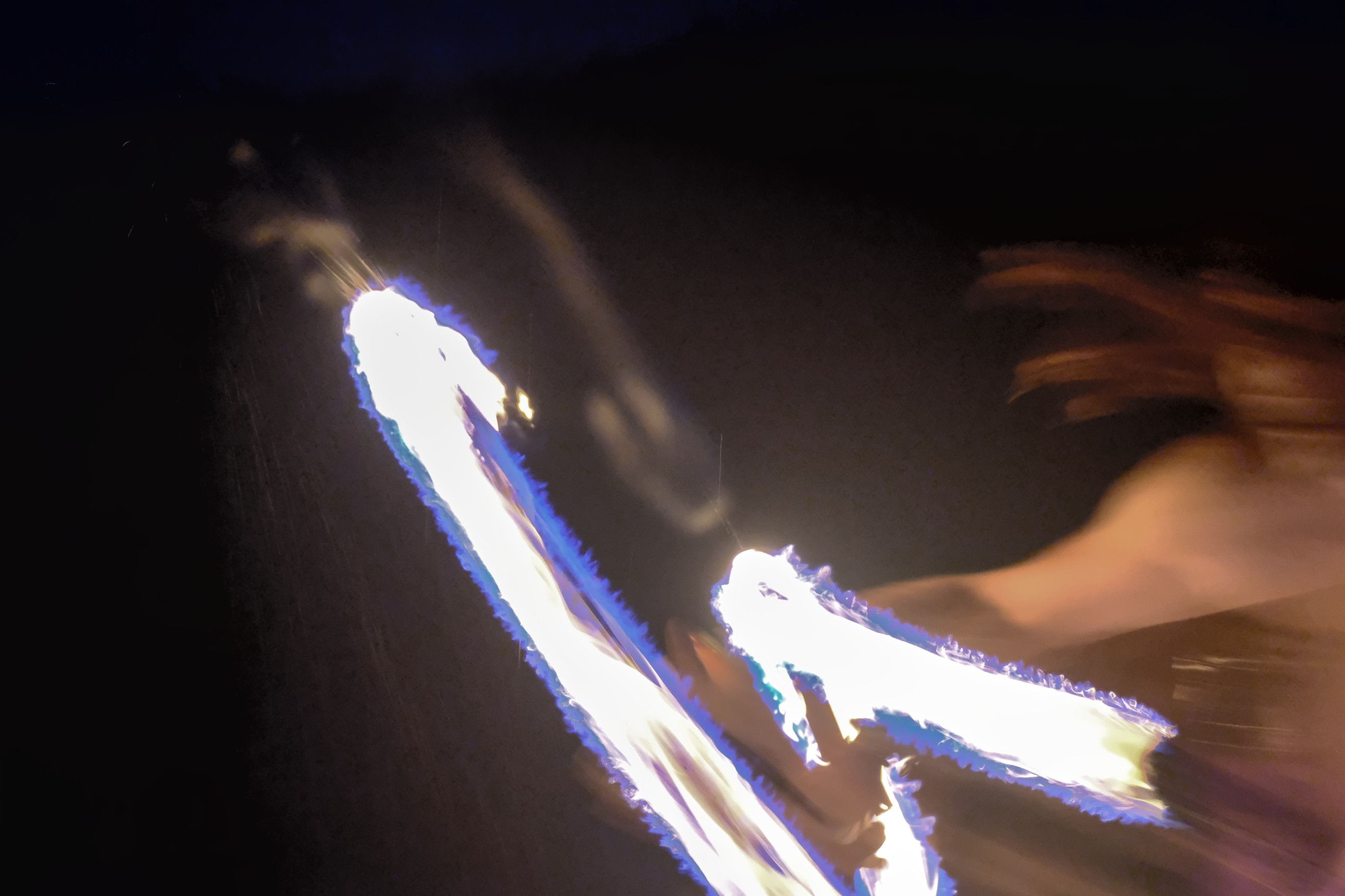 A very blurry person with very blurry fire from a long exposure relative to his motion. His hair looks like interesting brown snakes against a black background
