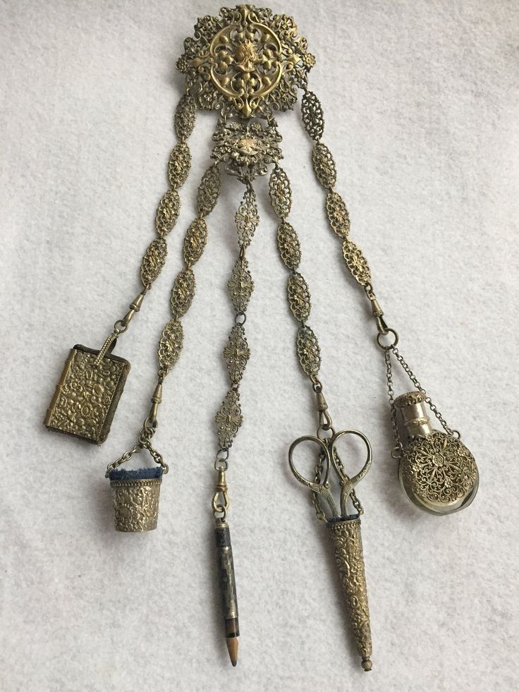 A chatelaine, holding scissors, a pencil, a thimble, smelling salts, and ?