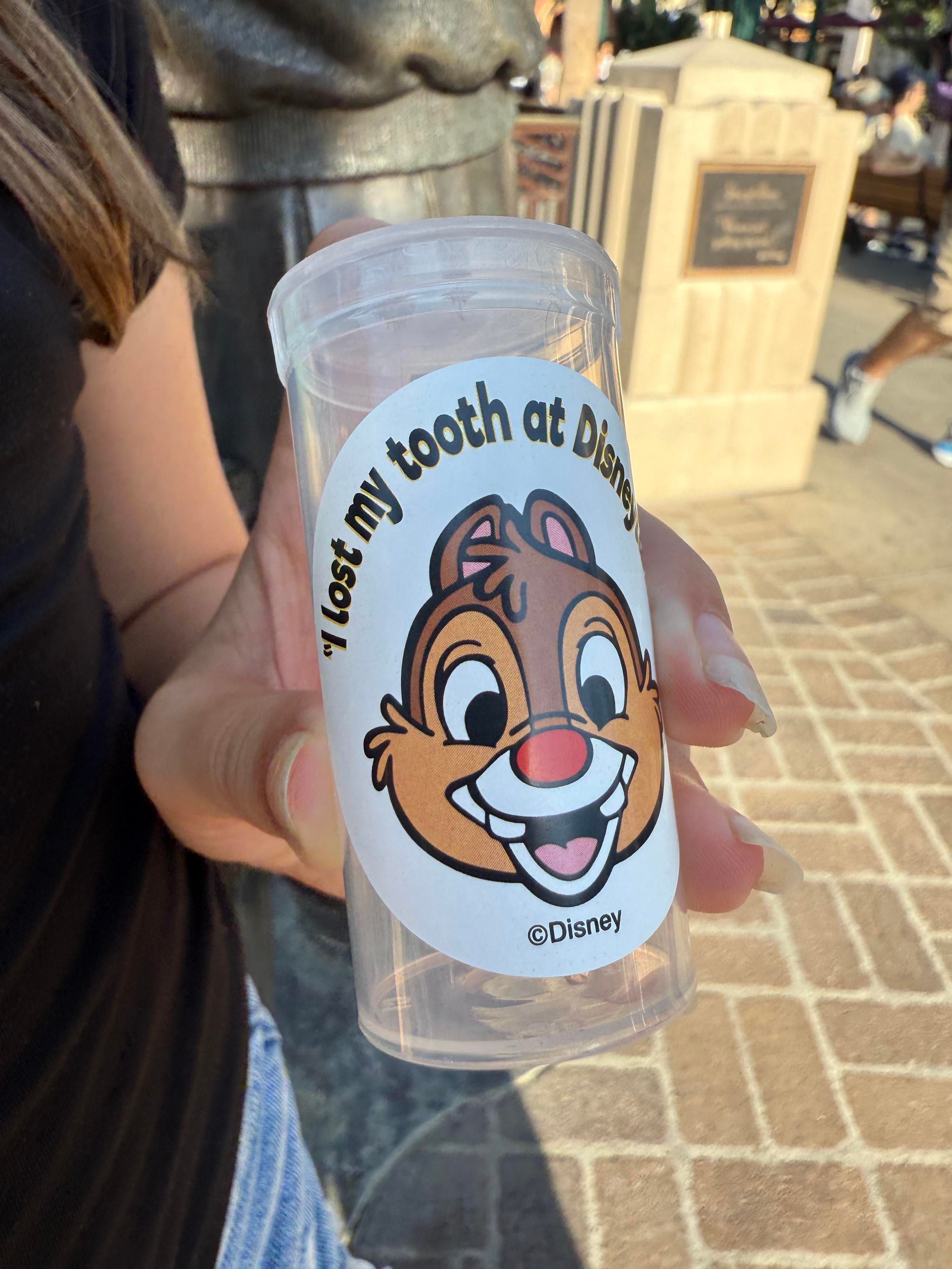 A picture of a small plastic bottle with a sticker that says “I lost my tooth at Disneyland“ and has a picture of chip… Or is it Dale?
