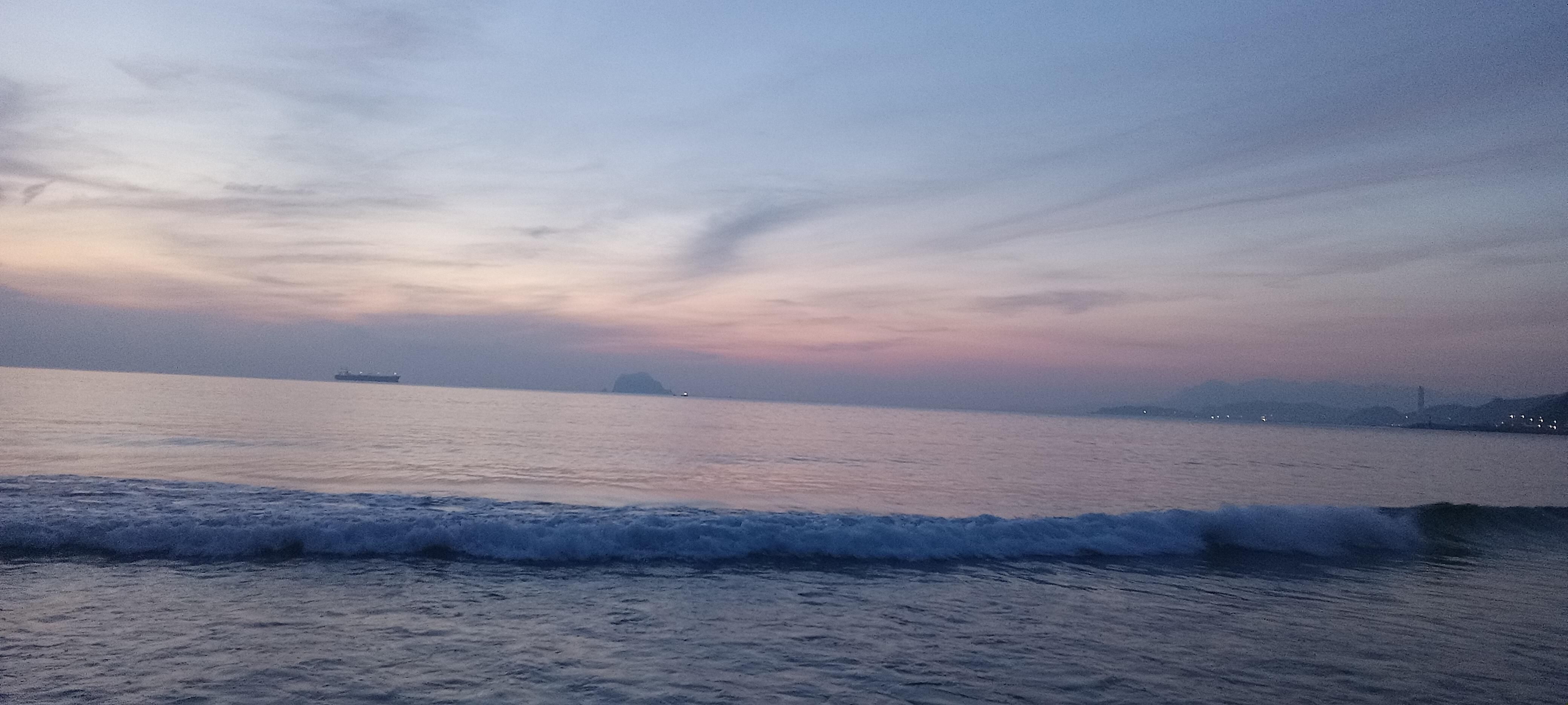 Gentle waves rolling in on a beach with a bit light coming in on the horizon