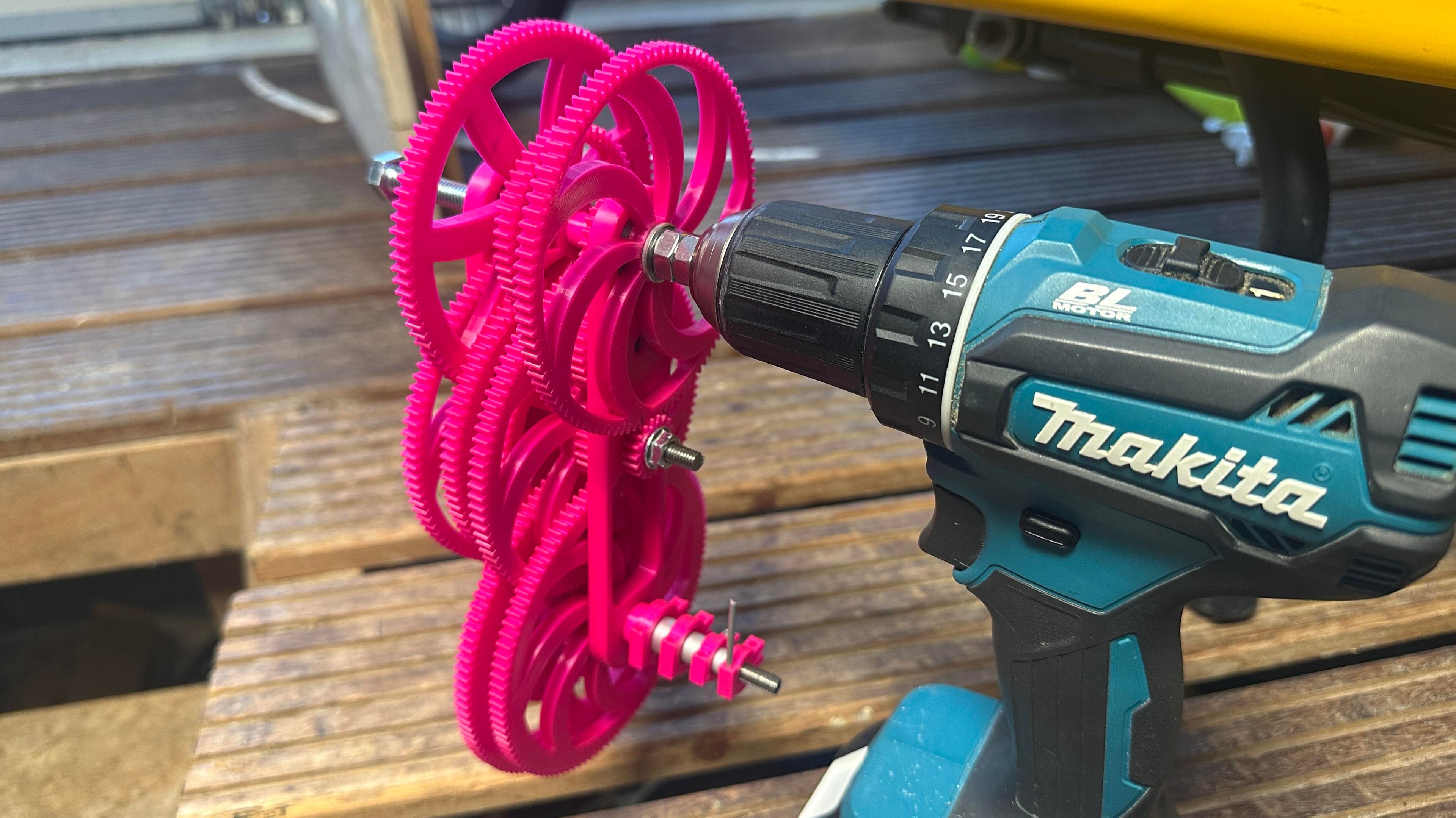 Complex gear train hooked to a power drill to drive it. 