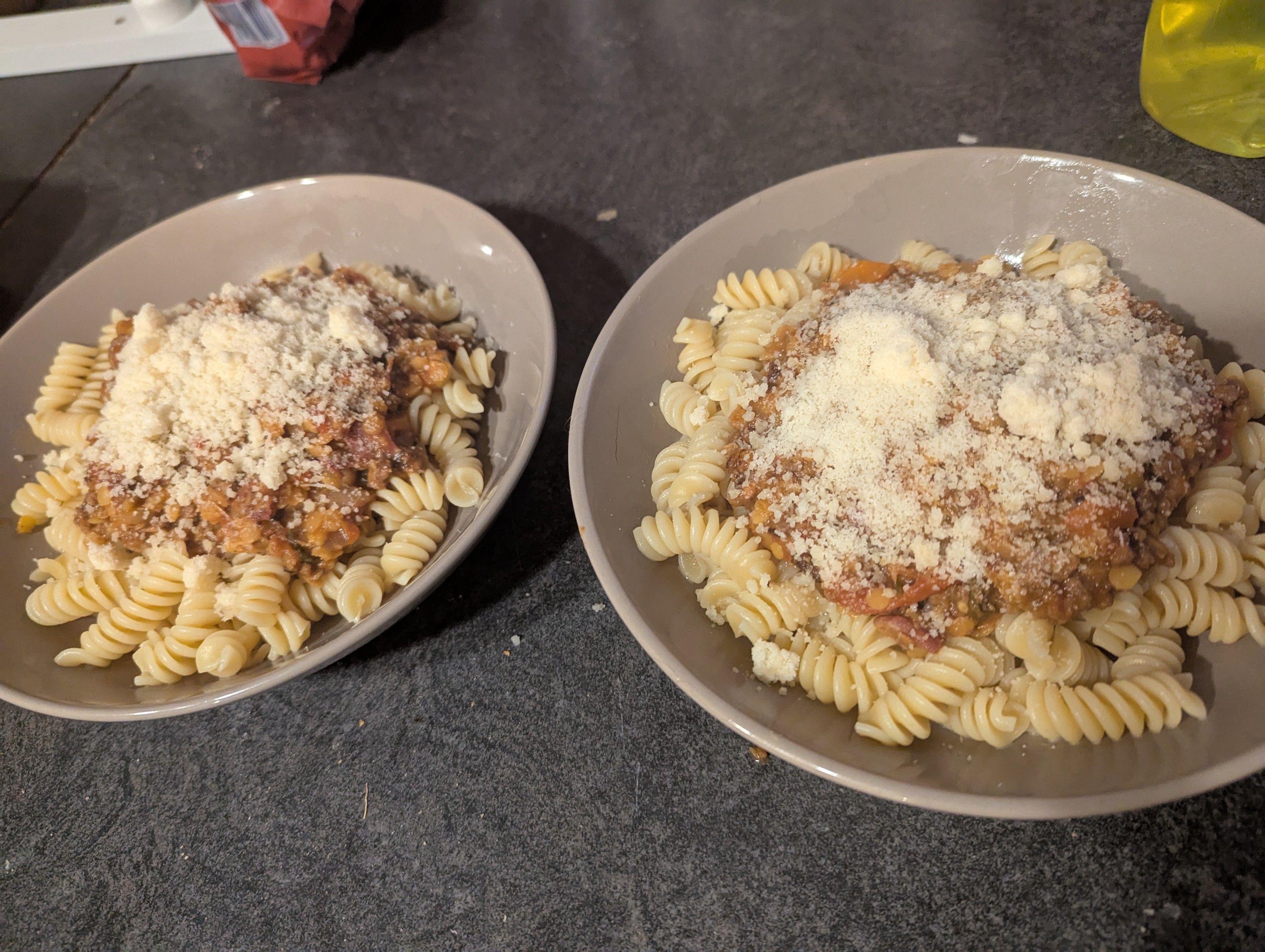 Two bowls of spag bol with lashings of parmesan.
