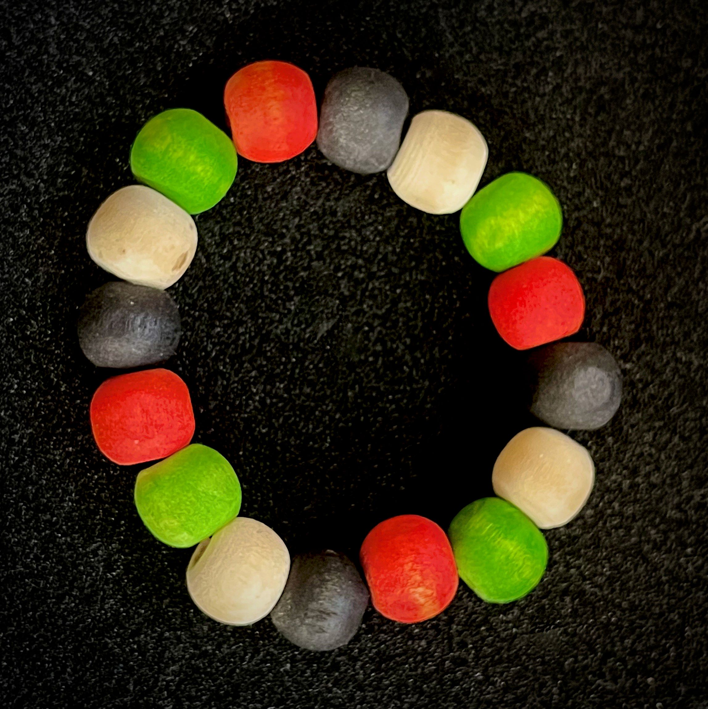 Picture of a beaded bracelet made up of Black, White, Red and Green dyed handmade wooden beads. 