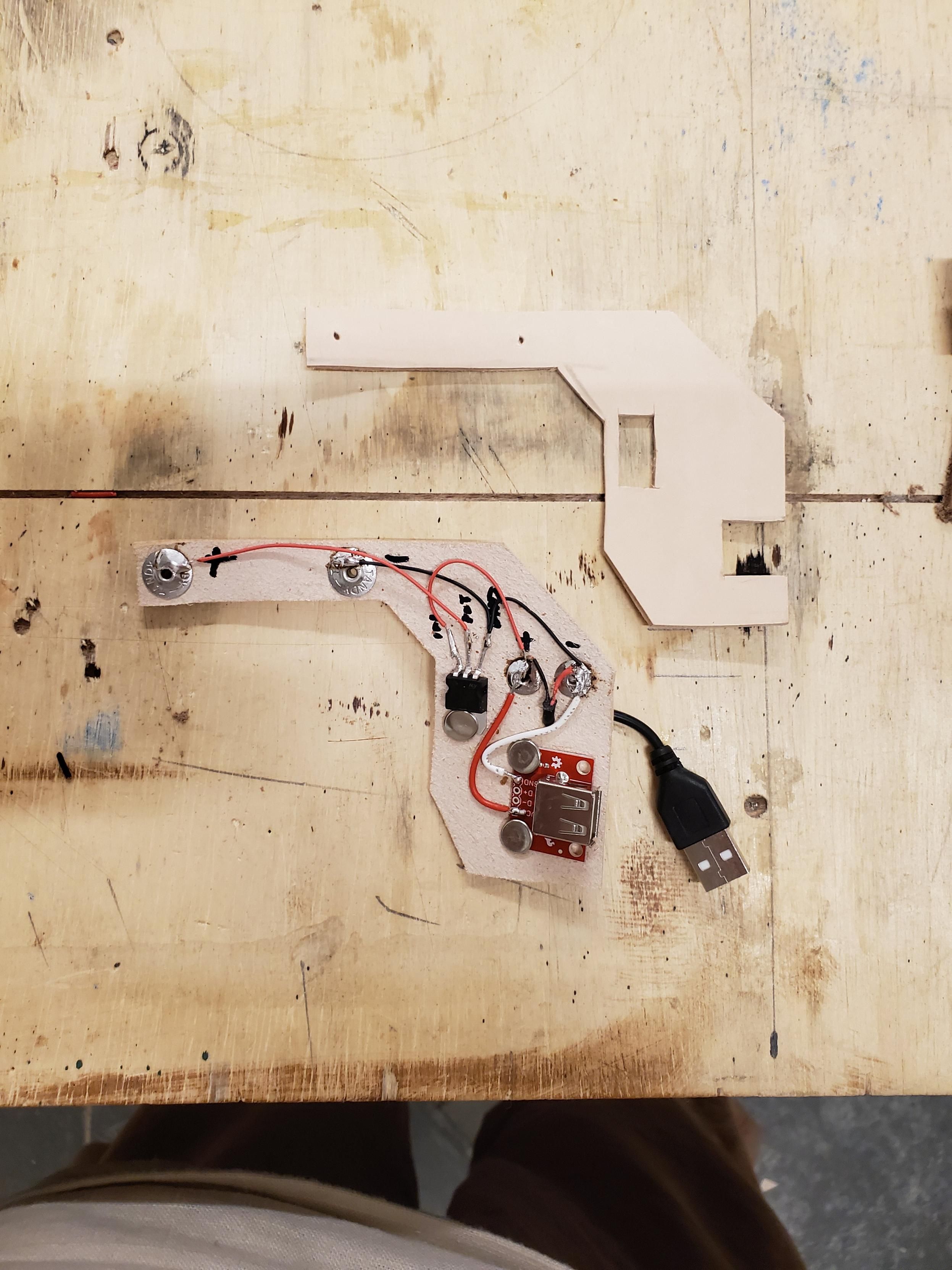 A piece of tooling leather with a voltage regulator and a USB connector rivetted into it.