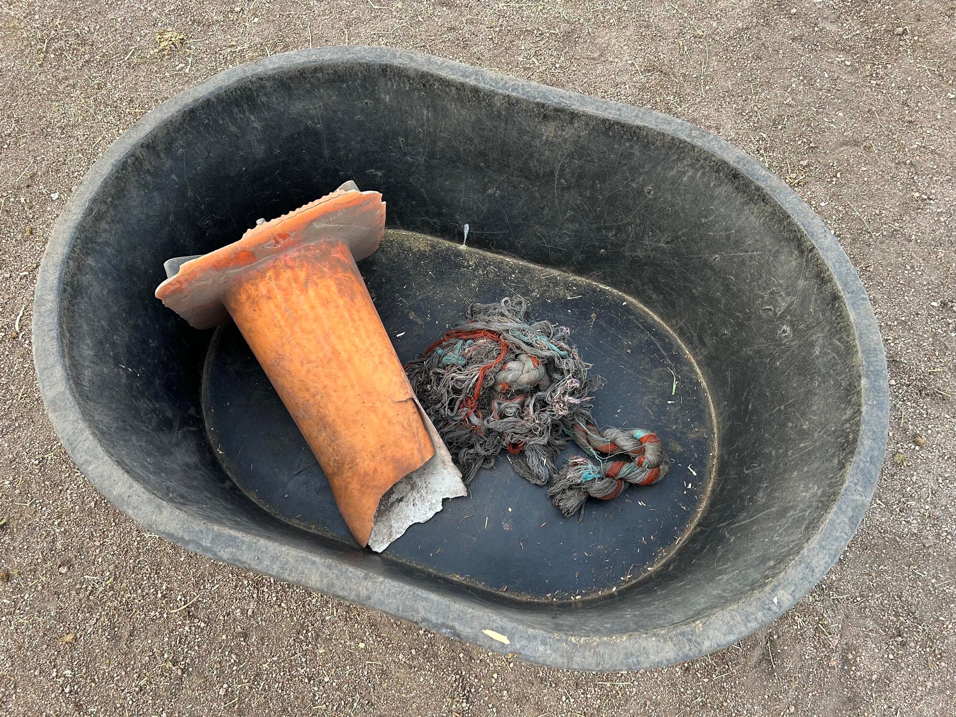 A large rubber tub containing a well chewed orange traffic cone and an almost unrecognizable rope pull toy 
