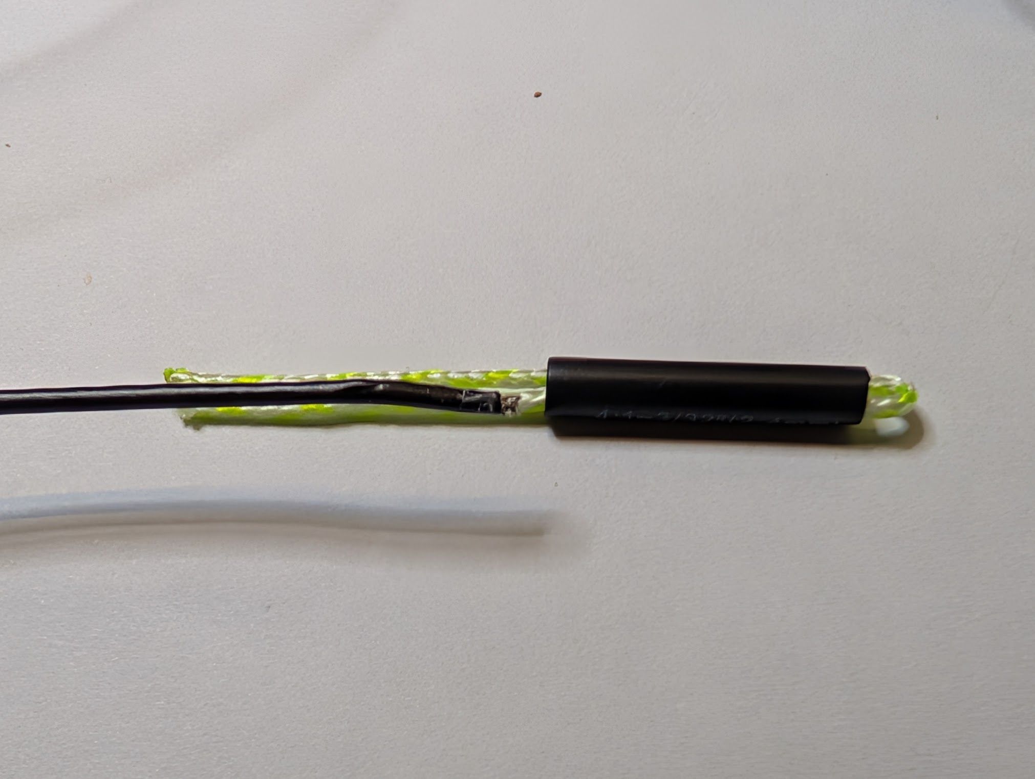 A piece of wire next to the tails of the doubled dacron line, ready to be inserted into the heat shrink