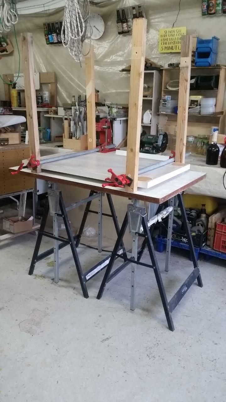 Un piano da tavolo appoggiato su due cavalletti in metallo.
Sopra un piano più piccolo, con quattro zampe sorrette da strettoi a vite, tanto per studiare come sistemare il tutto.