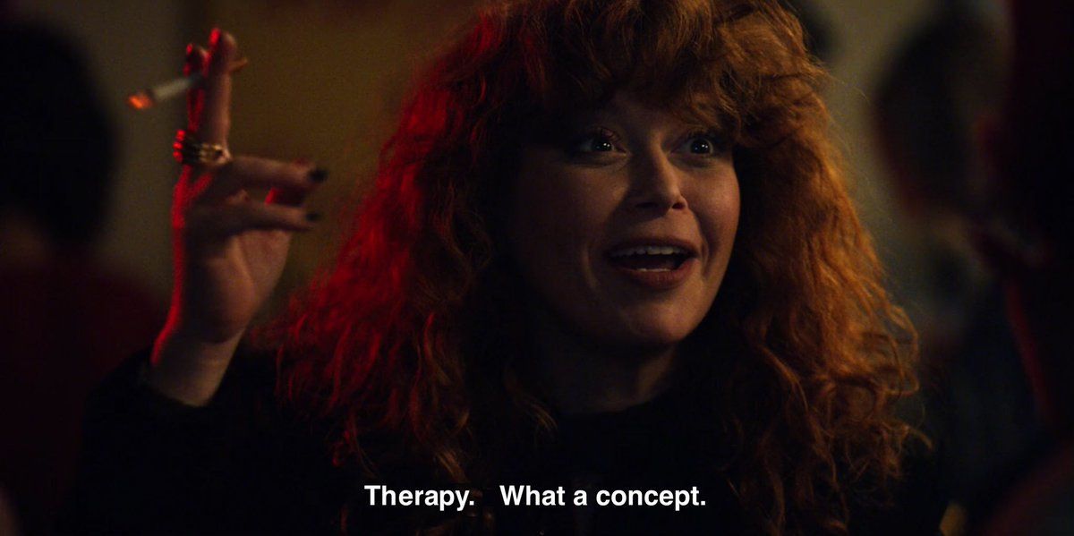 actress Nadia Vuvlokov with a lit cigarette in her raised right hand wearing a look of surprise/joy at someone off-camera. the caption has been edited to say "Therapy. What a concept." where "Therapy" was originally "Thursday"