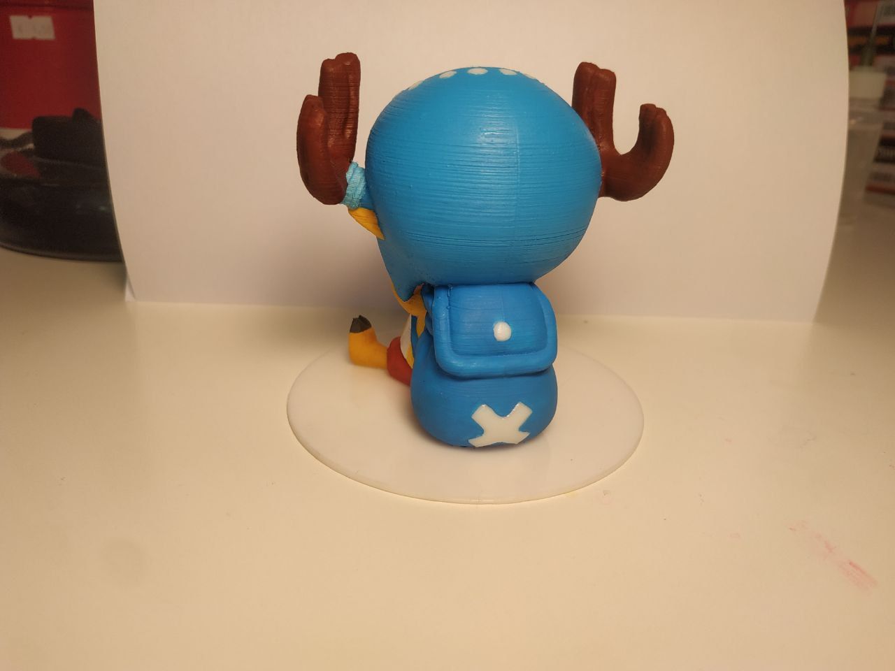 Modellino stampato in 3d del personaggio di One Piece Tony Chopper visto da dietro con zaino blu con croce bianca.
