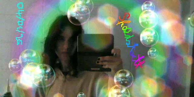 Selfie allo specchio del bagno con il new 3DS XL, effetti festa con bolle e riflessi, con la felpa da casa e una ciocca di capelli davanti all'occhio destro.
Sulla foto sono scritti con pennarello blu "04/01/26" e con pennarello arcobaleno in corsivo "Sfaldatoctt"