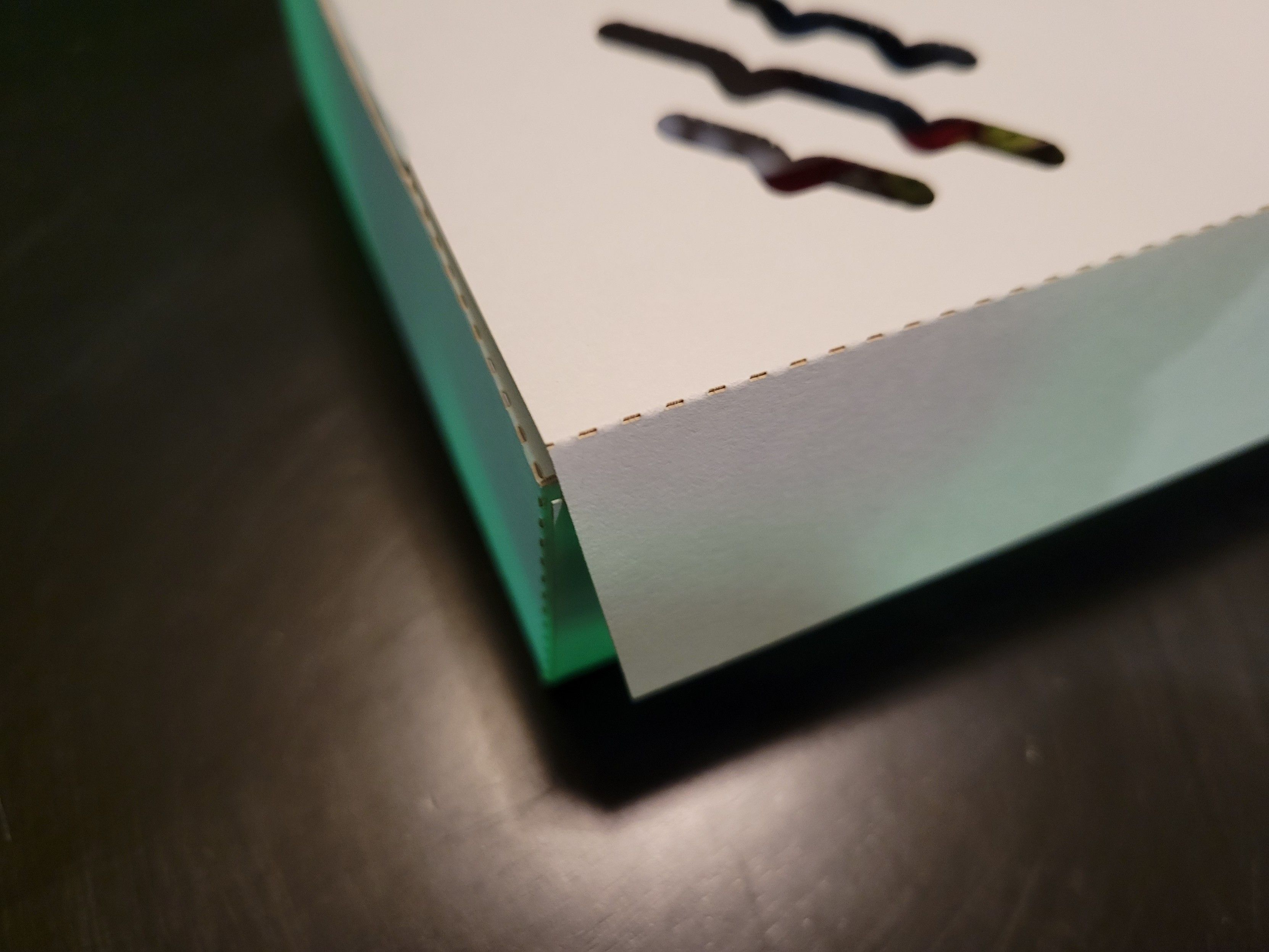 A close-up of the assembled box's front corner showing the dashed lines to help with folding the paper.