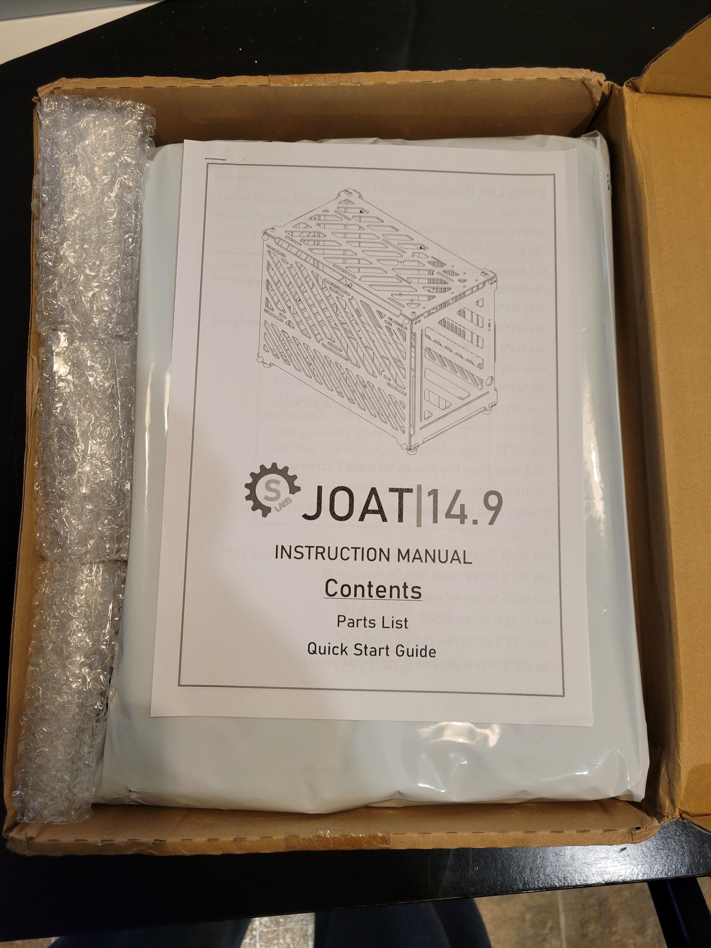 Open top of a box showing the manual for a JOAT 14.9 PC case.