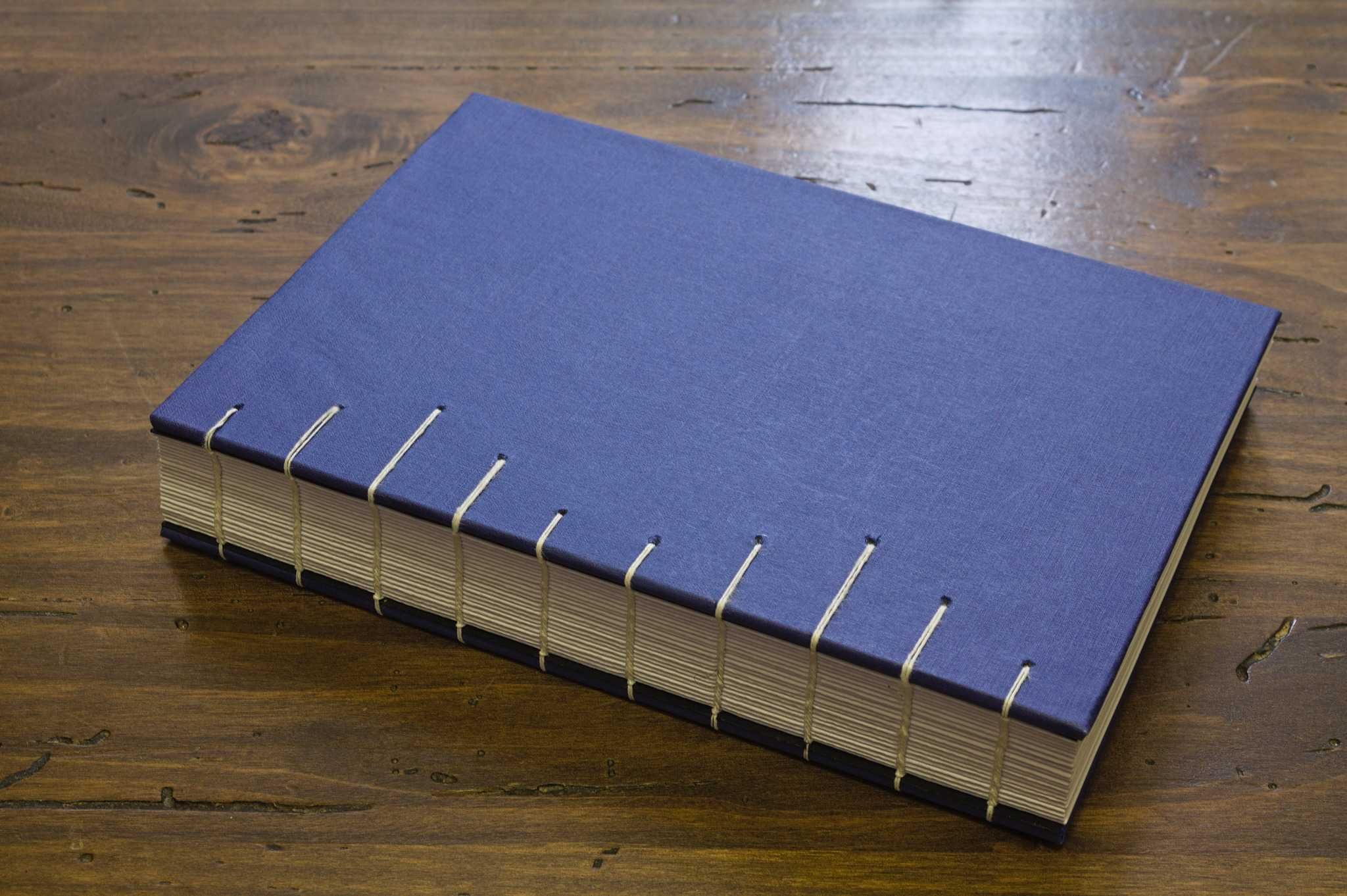 un quaderno con rilegatura copta visto dalla spina: è cicciotto, ma non in modo sproporzionato