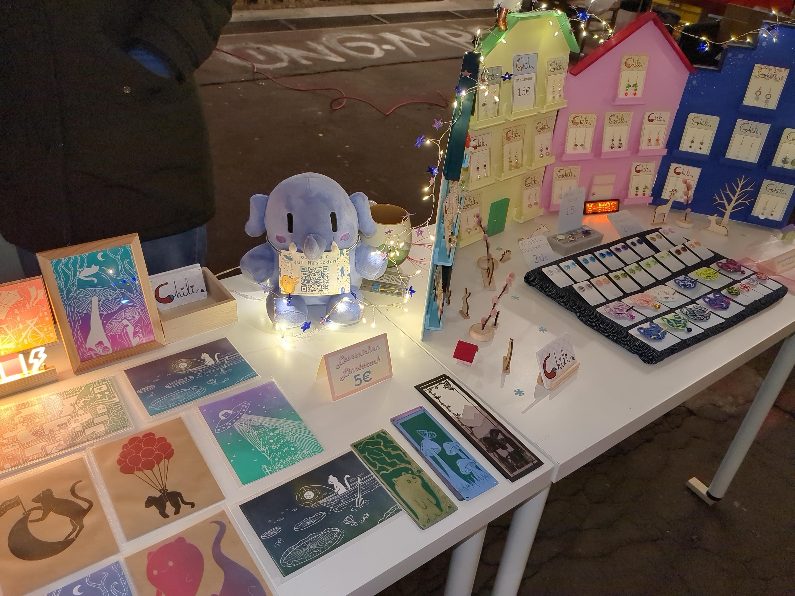 Photo of table with products. Prints and jewelry. In the middle a plushtodon