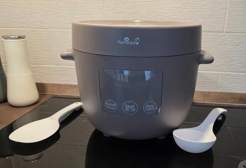 Cuociriso grigio scuro fotografata su un fornello a induzione con 2 spatole per riso accanto