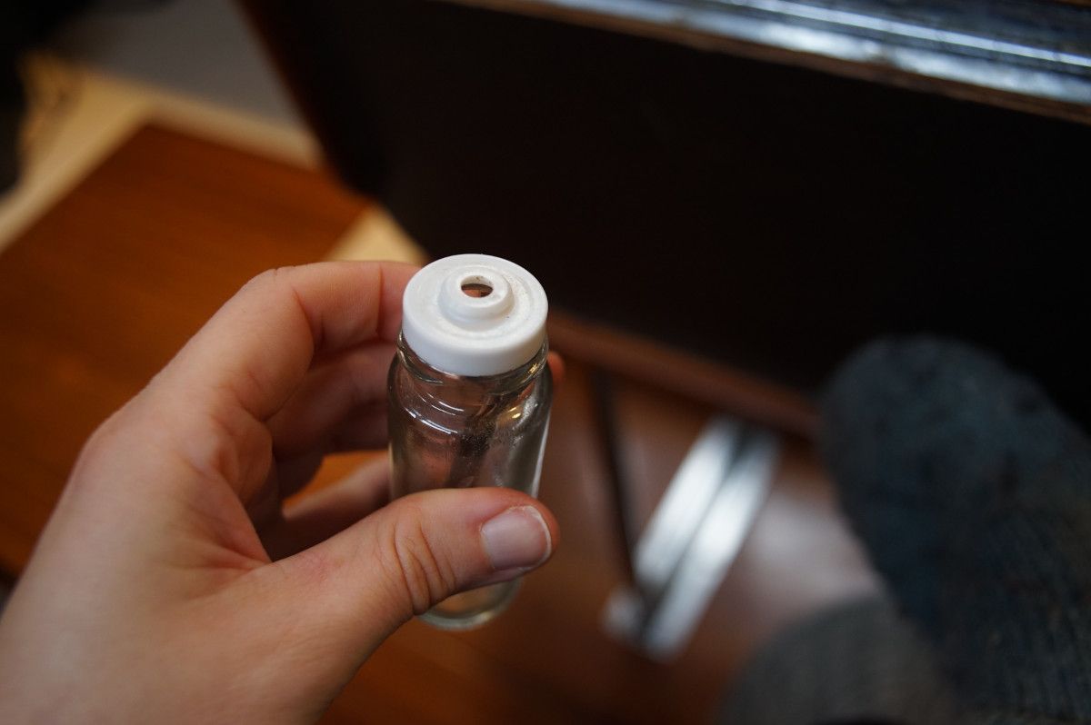a bottle of shichimi togarashi, with the red top off, showing the plastic bit that restricts the flow of spice to a smaller hole.
