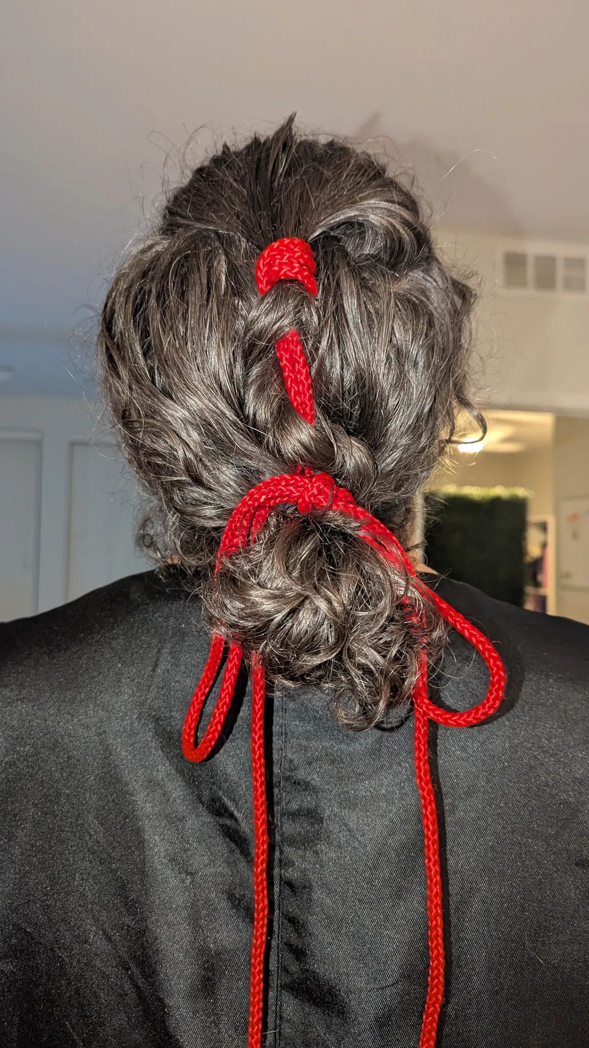 Long hair tied into a bun using a short cotton rope. 