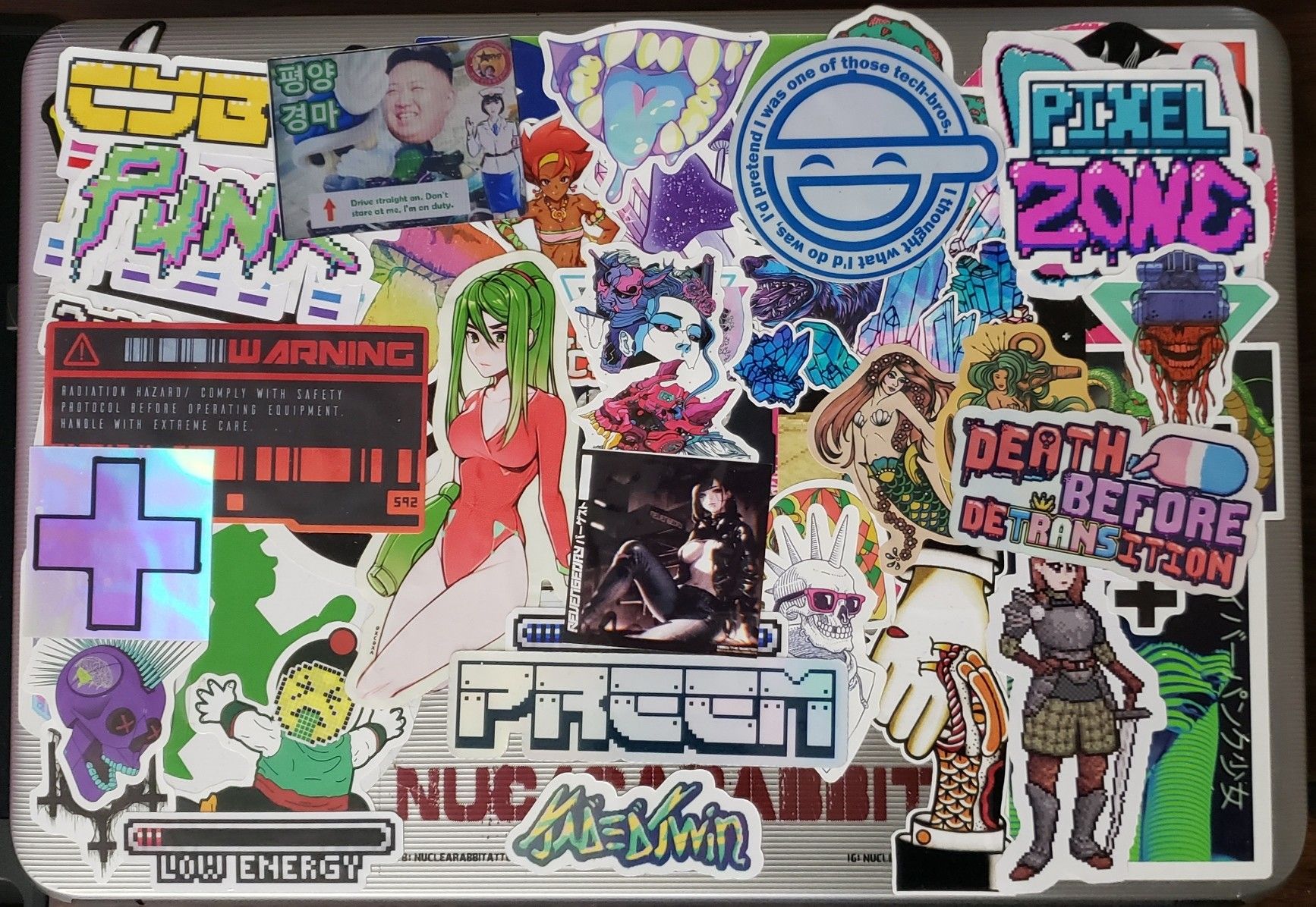 A laptop covered in too many stickers to accurately describe. Most are tech or punk themed.