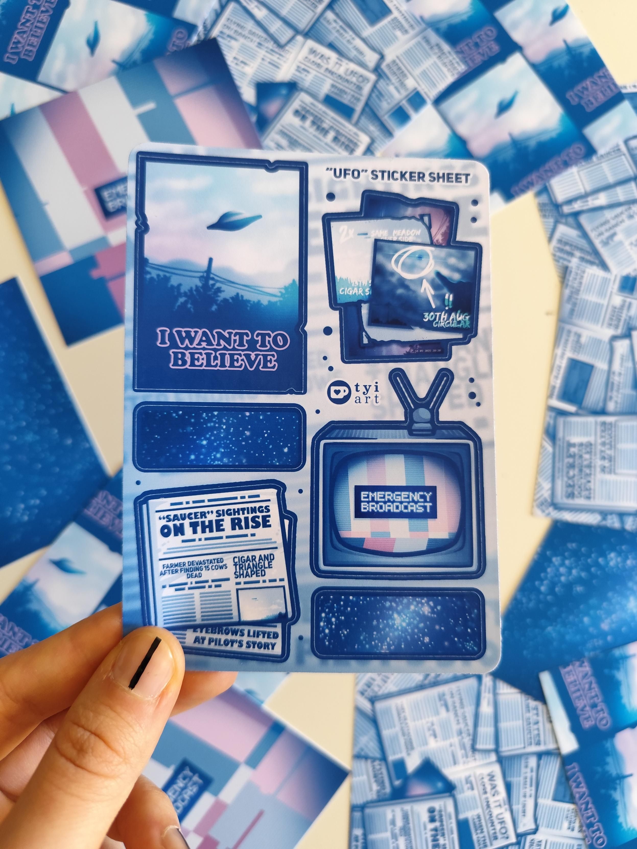 hand holding up a sticker sheet in the theme of UFOs and space