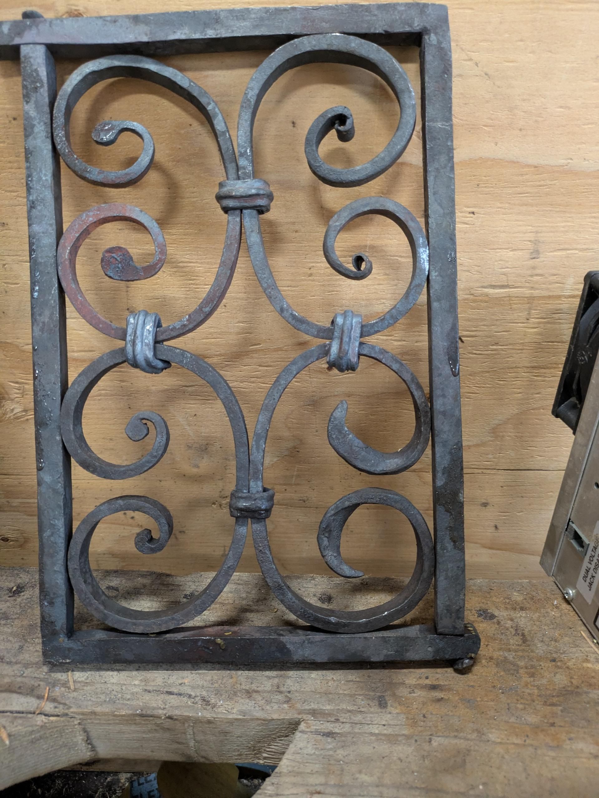 A roughly forged set of four double scrolls in a frame with ridged collars holding them together.