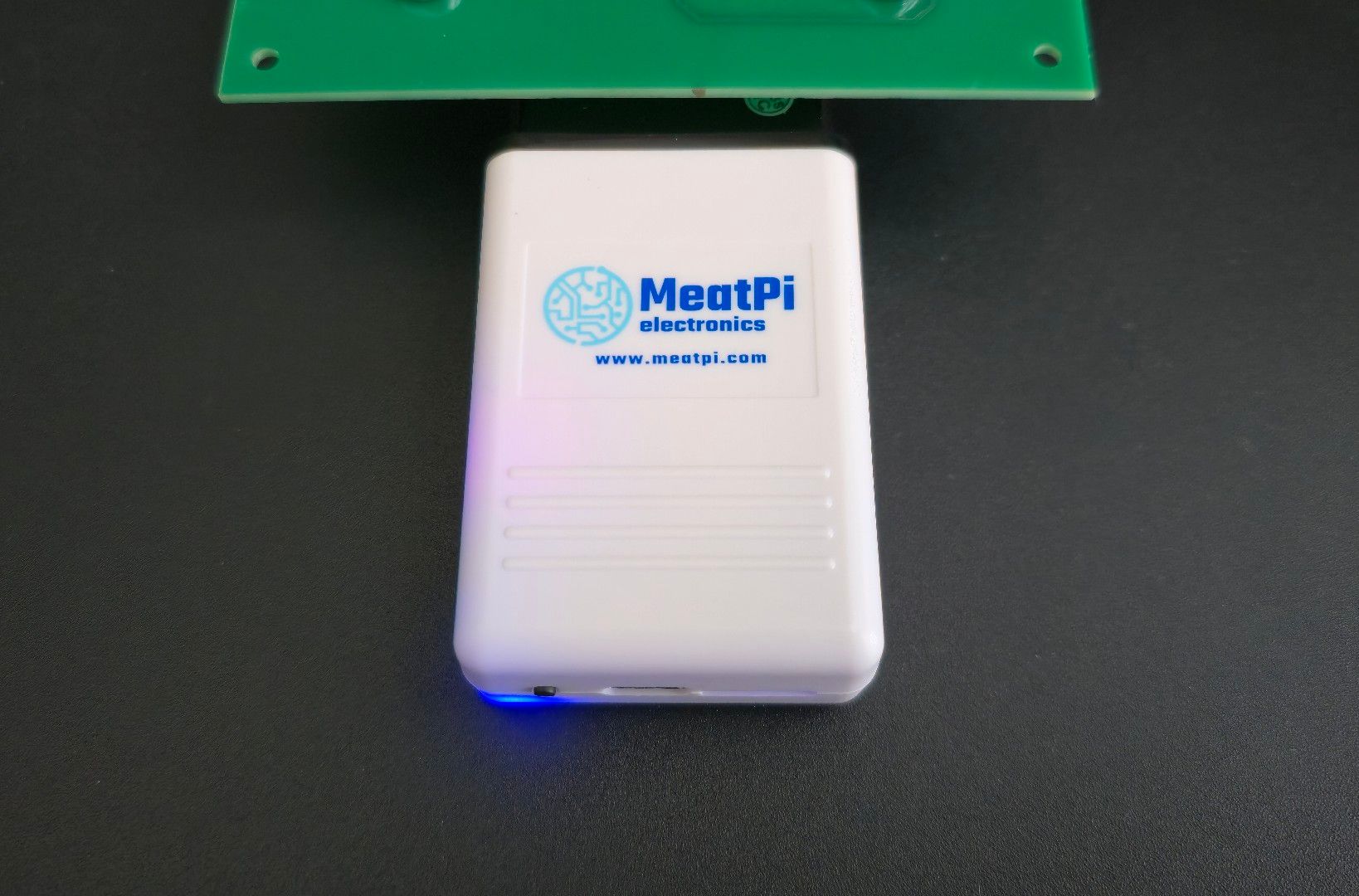 MeatPi Electronics auto diagnostic tool WiCAN PRO running plugged into OBD-2 simulator, with blue light on left bottom corner shining