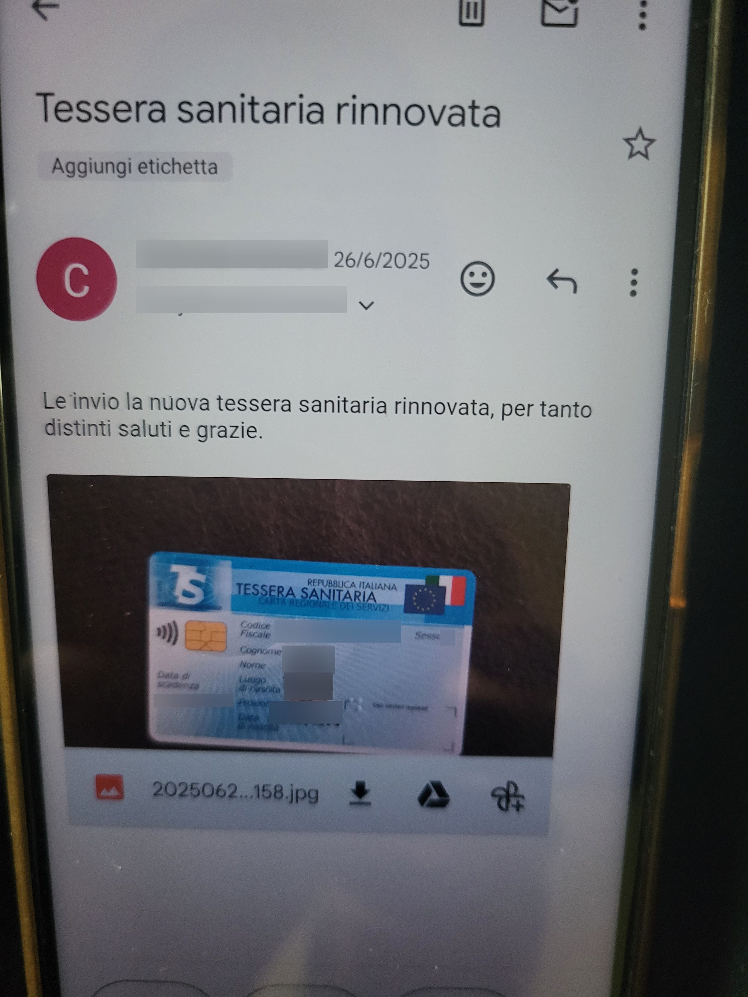 Foto di un telefonino che mostra una schermata con un app email (gmail) di un messaggio di posta elettronica e una immagine allegata in linea di una tessera sanitaria. I dati personali sono stati eliminati.