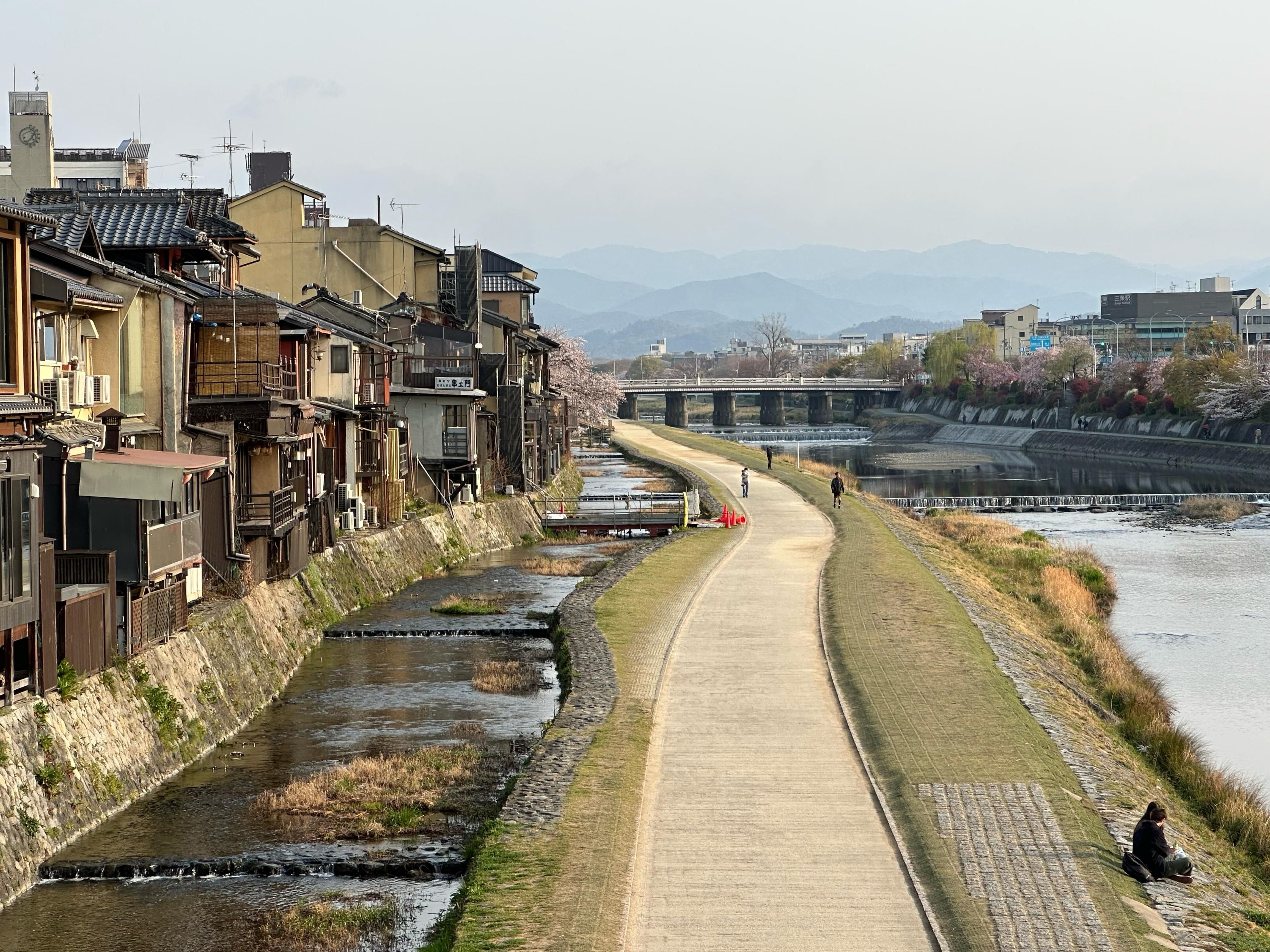 A path by a river and hills in the distance
