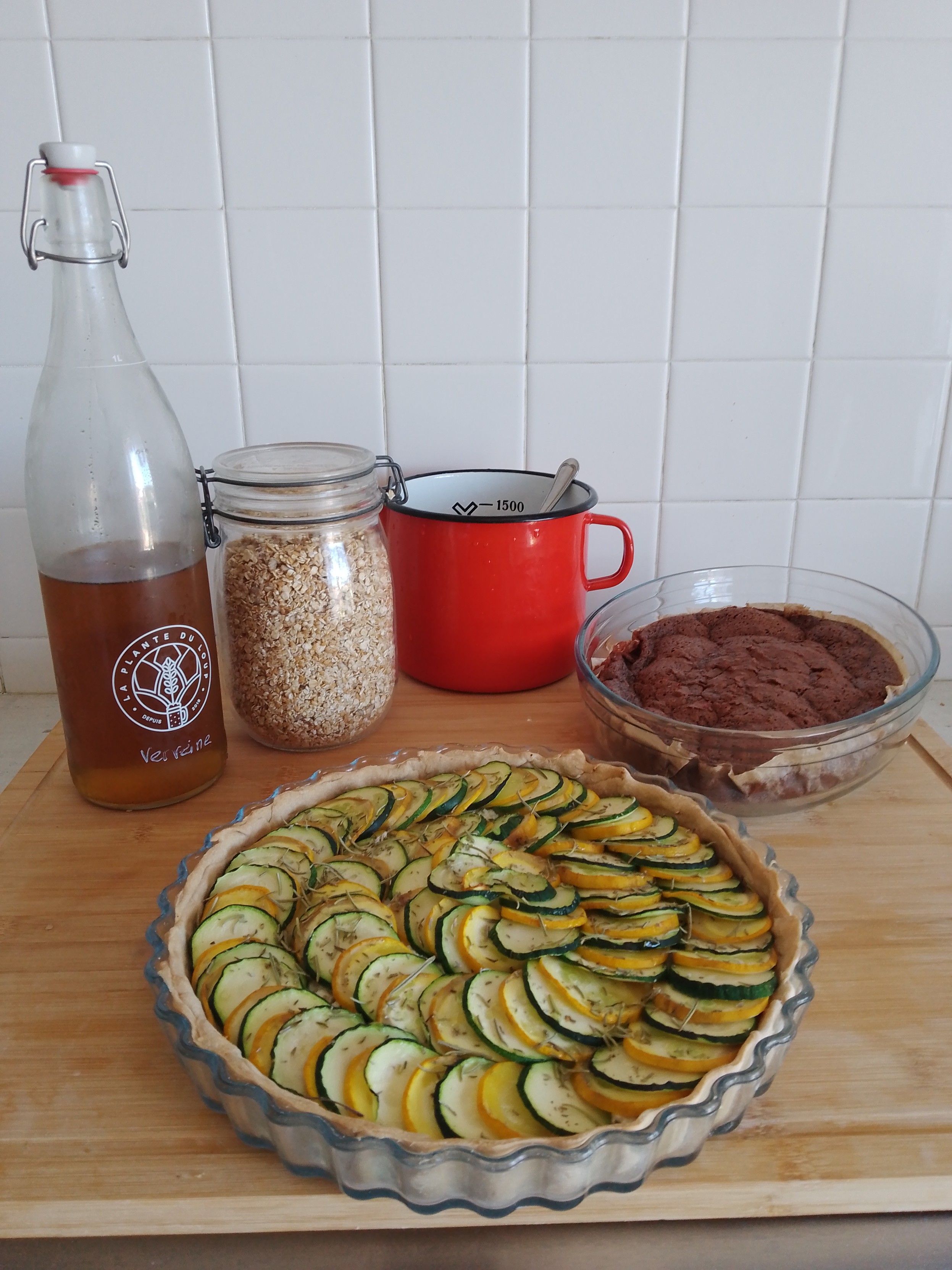 Photo de ce que j'ai préparé de matin. Sur une planche en bois avec des carreaux blancs en fond:
- une bouteille de sirop de verveine maison 
- un bocal de müesli maison
- un pot en métal émaillé rouge dans lequel marine une sumacade
- un fondant au chocolat qui m'a permis d'utiliser 400g de la monstro-courgette 
- la tarte aux courgettes de la photo précédente
