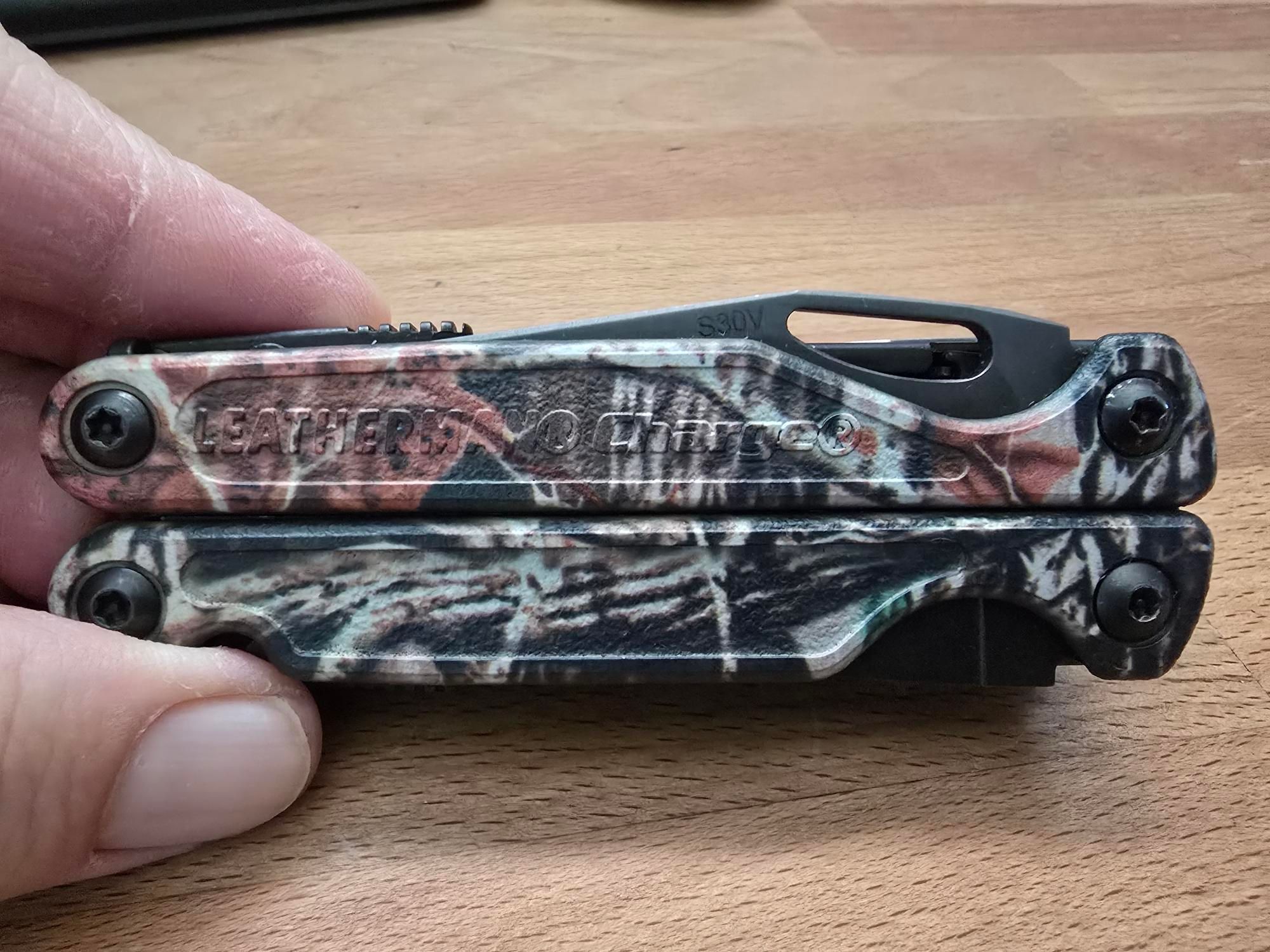 A Leatherman Charge TTi camo presentation side. The S30v blade steel mark is visible.