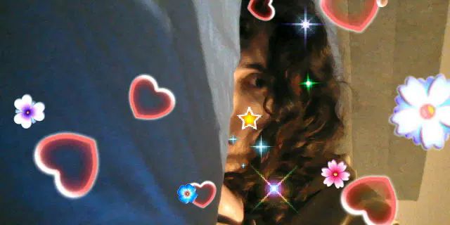 Io sul mio letto mezza nascosta dal cuscino, foto scattata e caricata dal 3DS con effetti di cuori e fiori a schermo