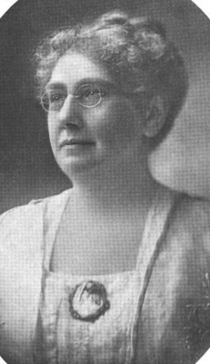Marion Mitchell Ochsner, from a 1917 publication; a sixty-ish white woman with grey hair in an updo, wearing glasses and blouse with a square neckline